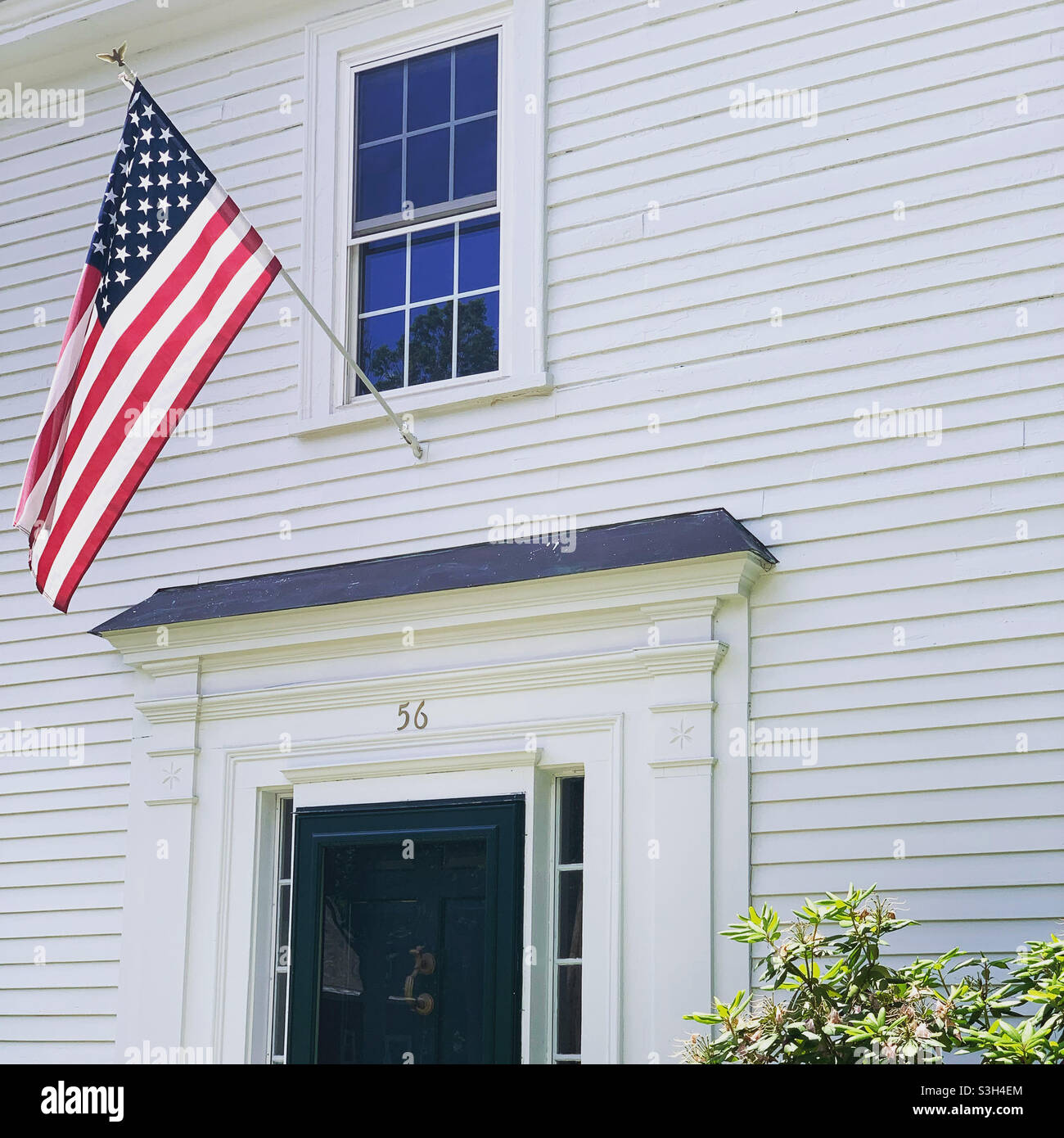 Una bandiera americana sopra la porta anteriore di una casa a Walpole, Contea di Cheshire, New Hampshire, Stati Uniti - Immagine stock catturata con smartphone