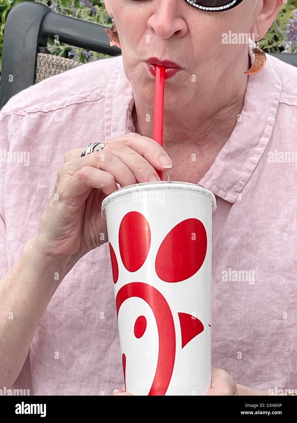Donna anziana che usa una cannuccia di plastica per bere la sua bevanda Chick-fil-A, New York, USA 2021 Foto Stock