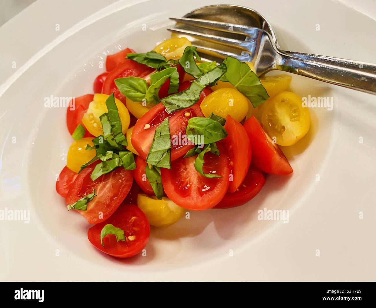 Piatto di pomodori freschi da fattoria a tavola servito con basilico e olio d'oliva a Milano Foto Stock