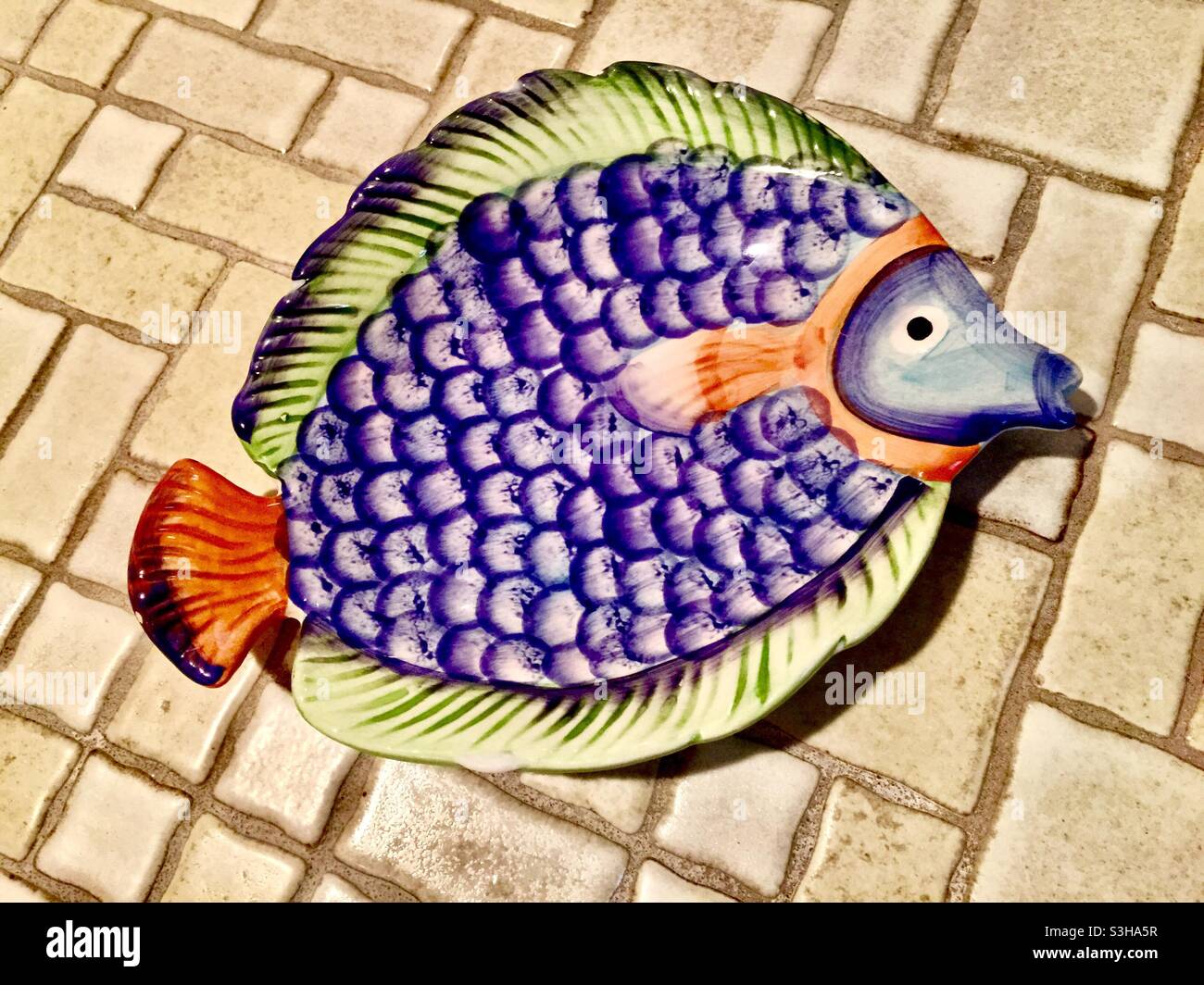 Un piatto di sapone colorato a forma di pesce su un bancone piastrellato, Ontario, Canada - Immagine stock catturata con smartphone