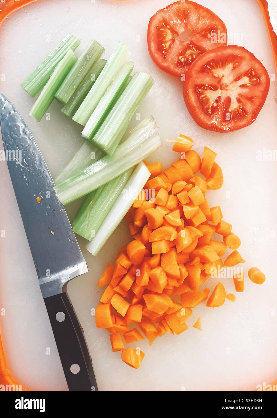 Verdure a dadini e un coltello grande su un piano di taglio di cucina residenziale, USA Foto Stock