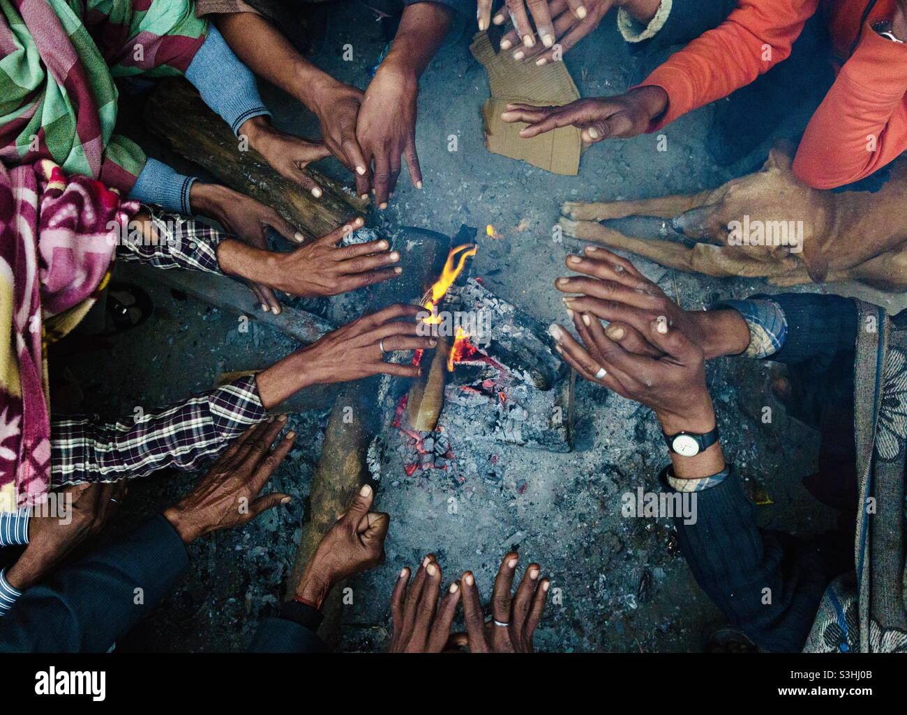Le mani riscaldano la mattina presto in inverno a Varanasi, India Foto Stock