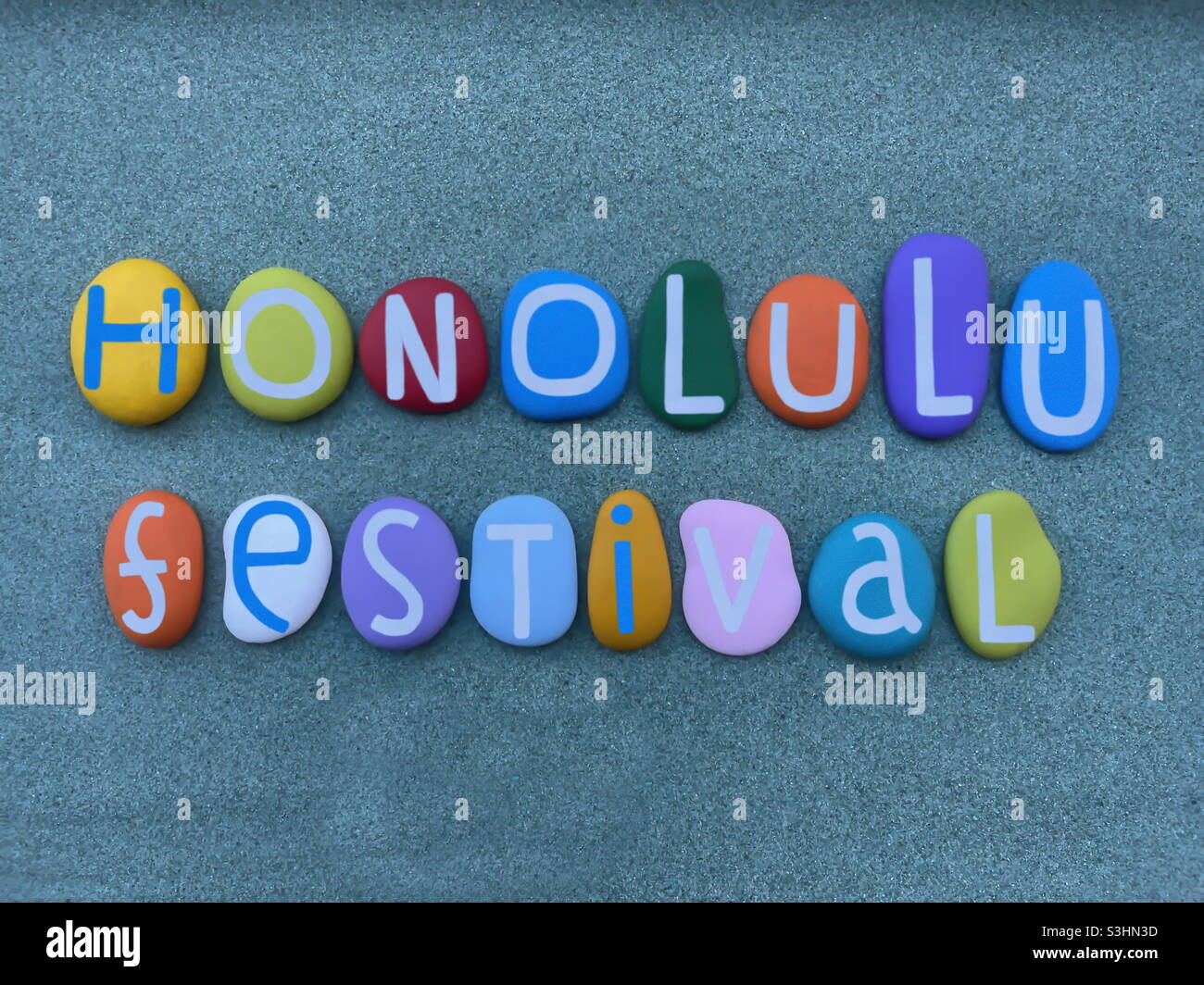 Honolulu Festival, il più importante evento culturale delle Hawaii, testo creativo composto da lettere in pietra multicolore sulla sabbia verde - Immagine stock catturata con smartphone