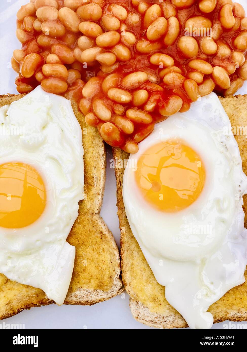 Due uova fritte sul pane tostato con fagioli cotti Foto Stock