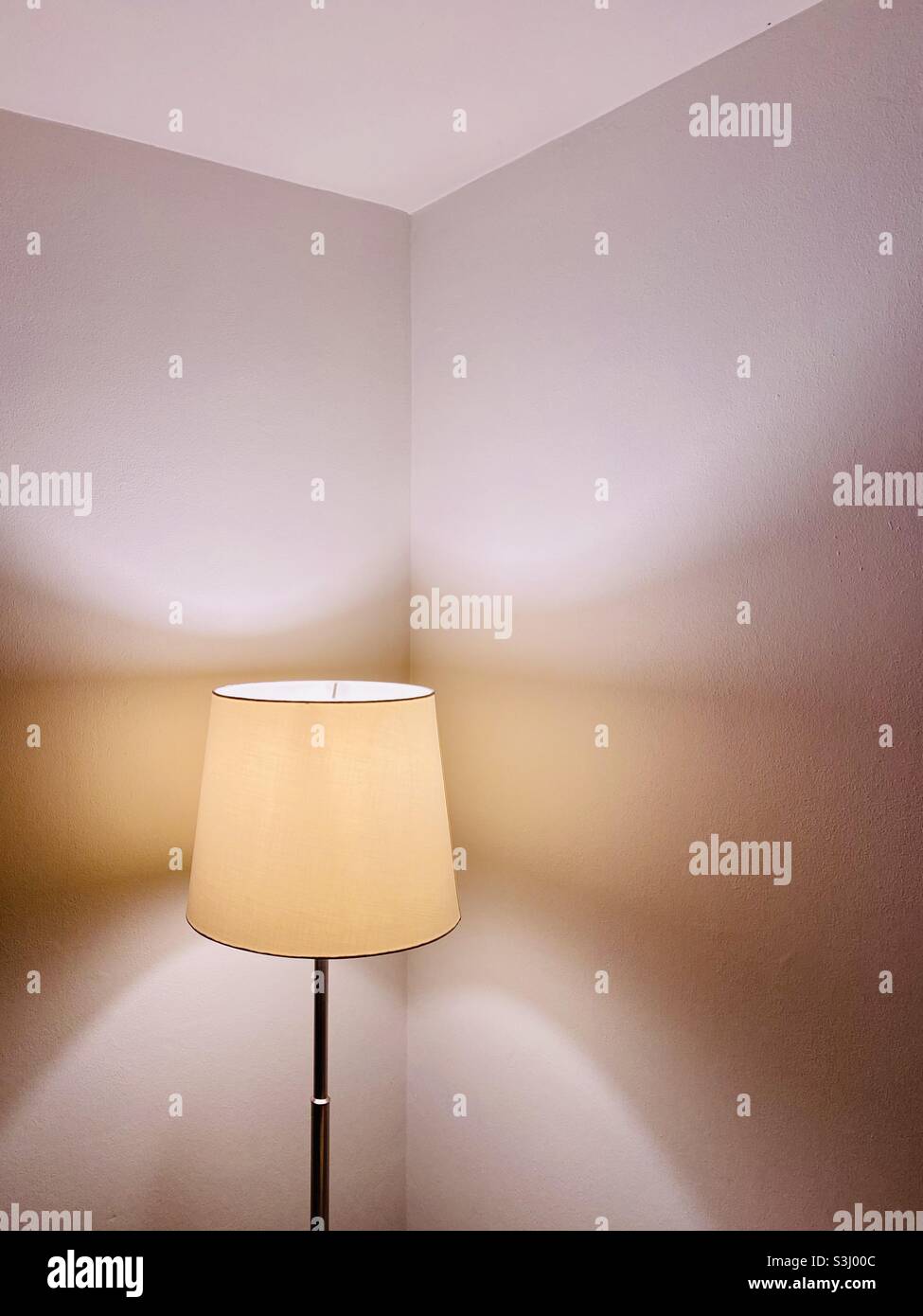 Lampada illuminata che illumina le pareti in un angolo - Immagine stock catturata con smartphone