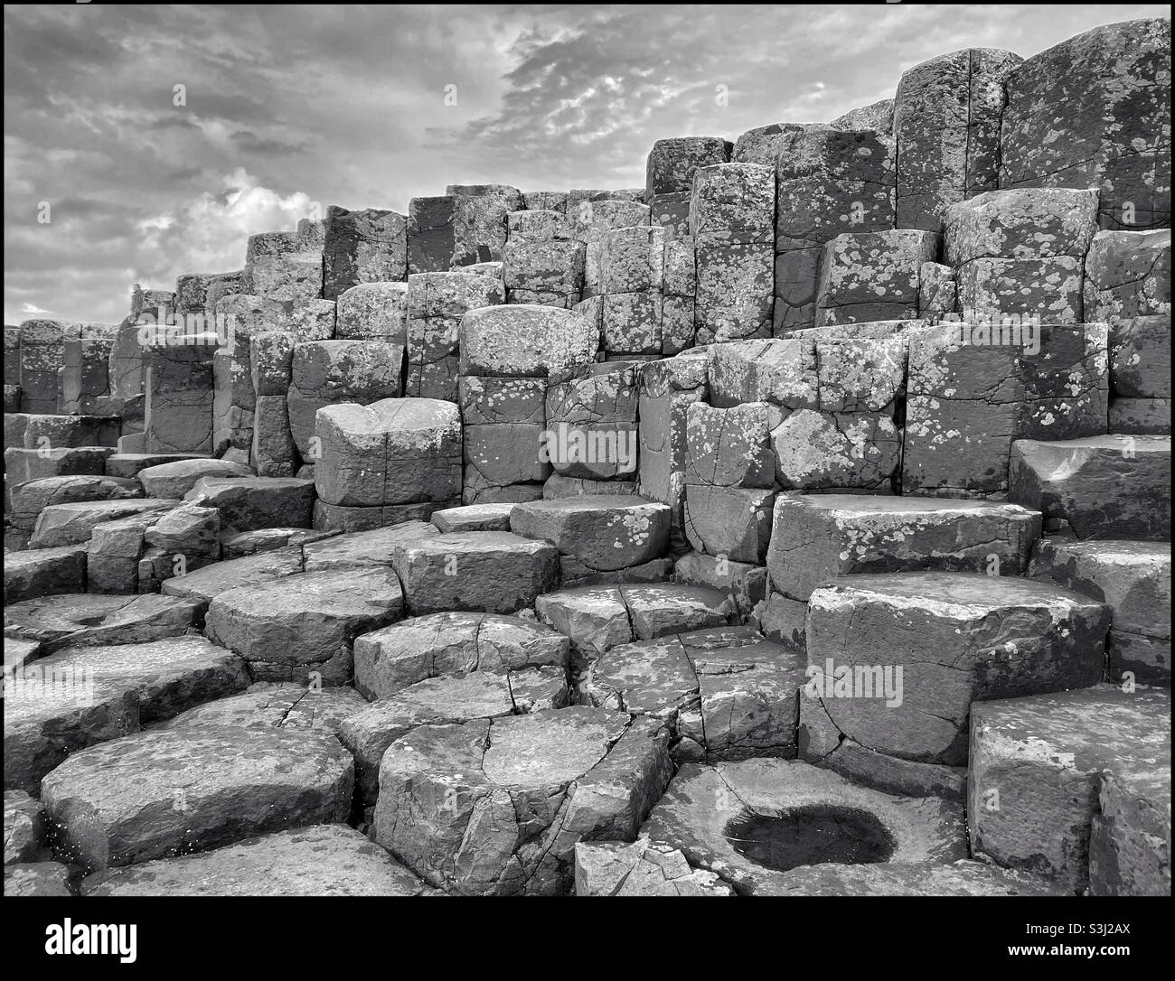 Un'immagine monocromatica di alcune delle colonne basaltiche che formano l'area conosciuta come Selciato del Gigante nell'Irlanda del Nord. Questo fenomeno geologico si è formato circa 60 milioni di anni fa a causa di eruzioni vulcaniche - Immagine stock catturata con smartphone