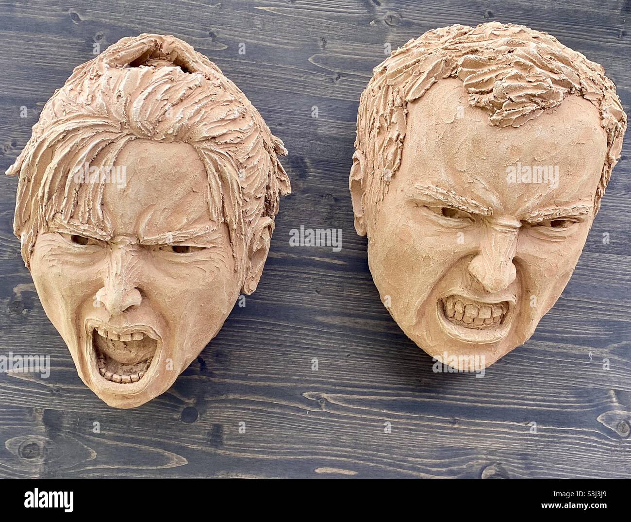 Scultura in argilla di due facce che interagiscono con lo sfondo in legno - Immagine stock catturata con smartphone