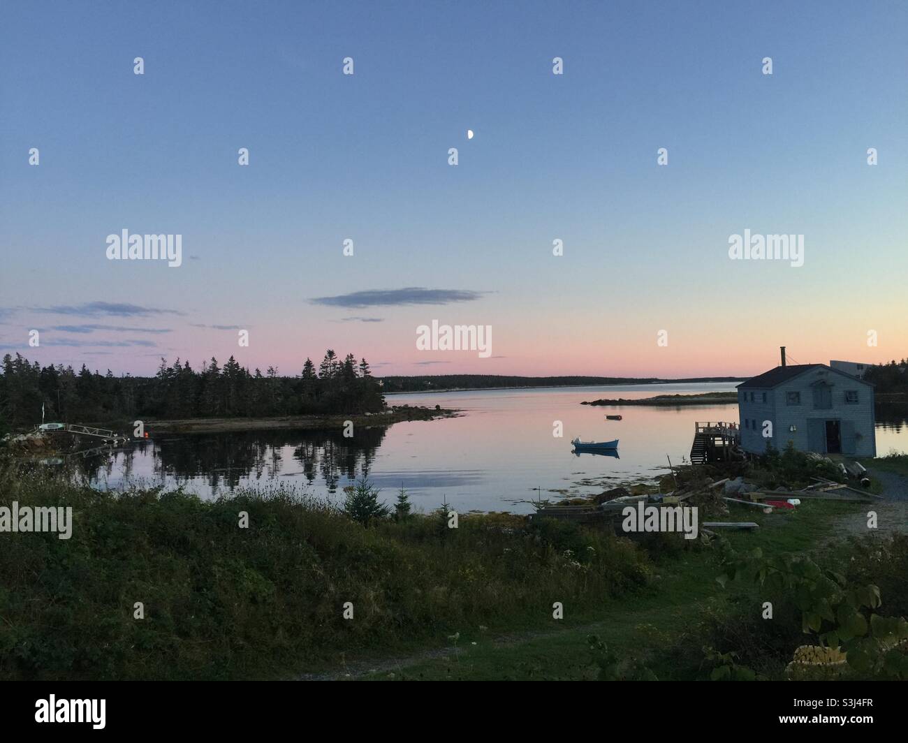 Una scena marittima al crepuscolo con la luna in una baia dell'Oceano Atlantico, Halifax, Canada. Pace, calma, fine giornata Foto Stock