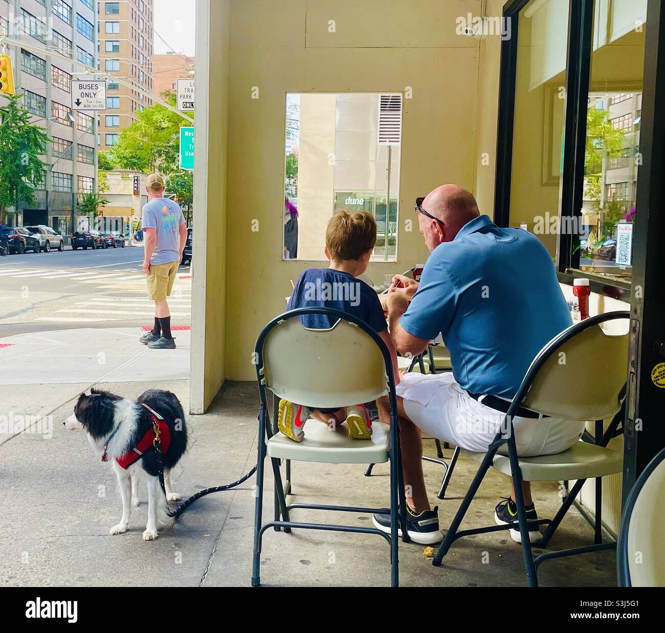 Un uomo, un ragazzo e un cane che mangiano fuori Foto Stock