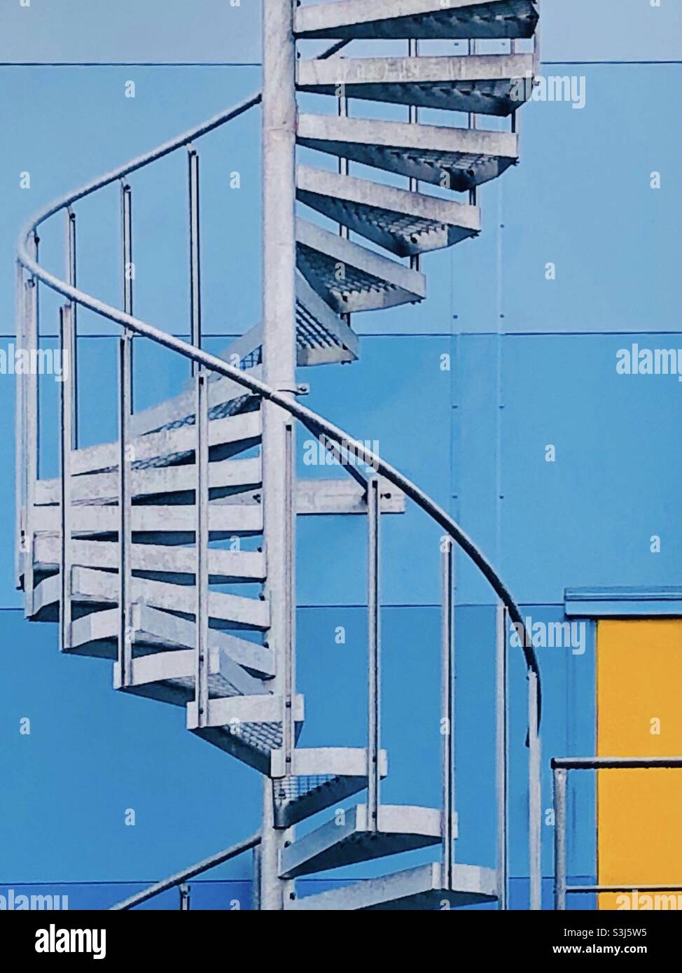 Scala a chiocciola sulla facciata di un edificio magazzino. - Immagine stock catturata con smartphone