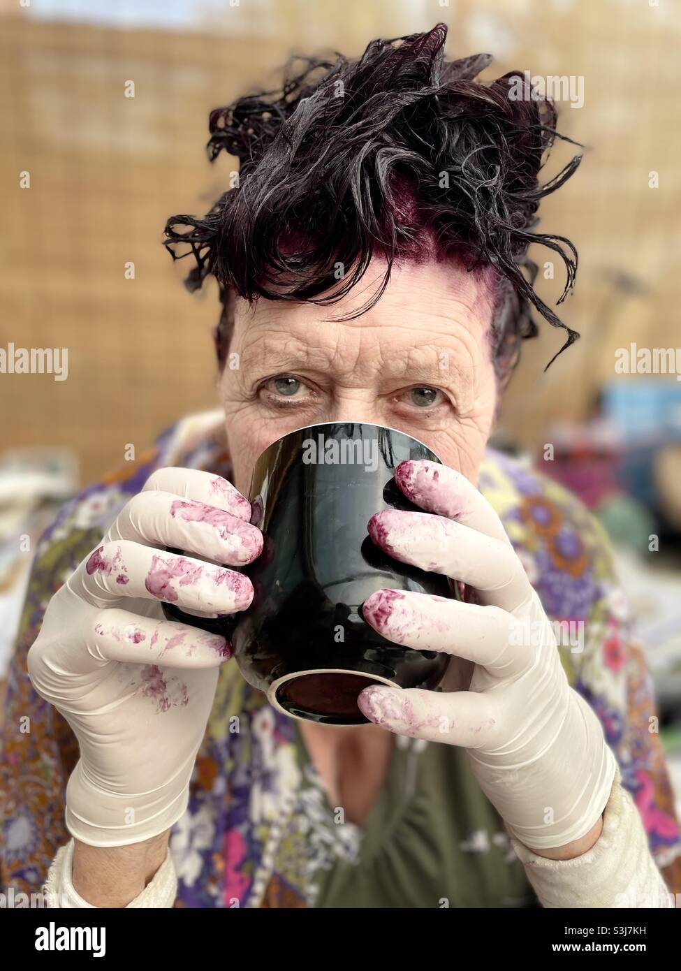 Donna che ha un caffè mentre il suo colore dei capelli si sviluppa Foto Stock