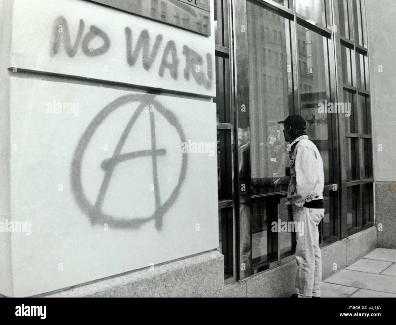 L'uomo che si occupa di costruire con graffiti SENZA simbolo di anarchia DI GUERRA - Immagine stock catturata con smartphone