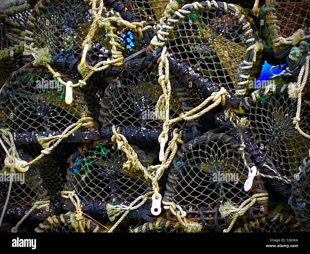 Primo piano di una pila di vasi di aragosta vuoti con corde utilizzate per la pesca in mare nelle barche - Immagine stock catturata con smartphone