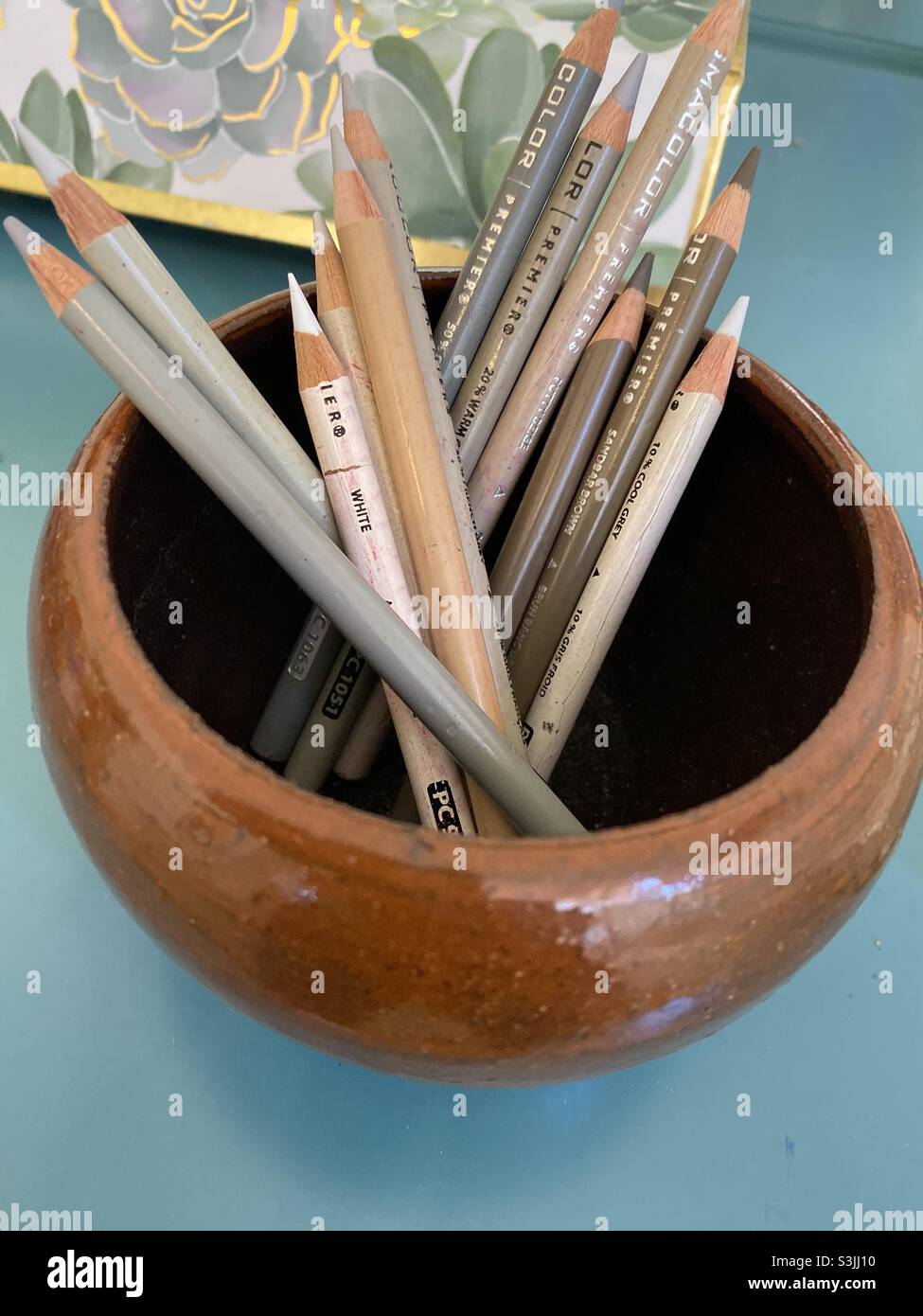 Tavolozza di colori neutri di matite colorate in una ciotola di ceramica marrone. Foto Stock