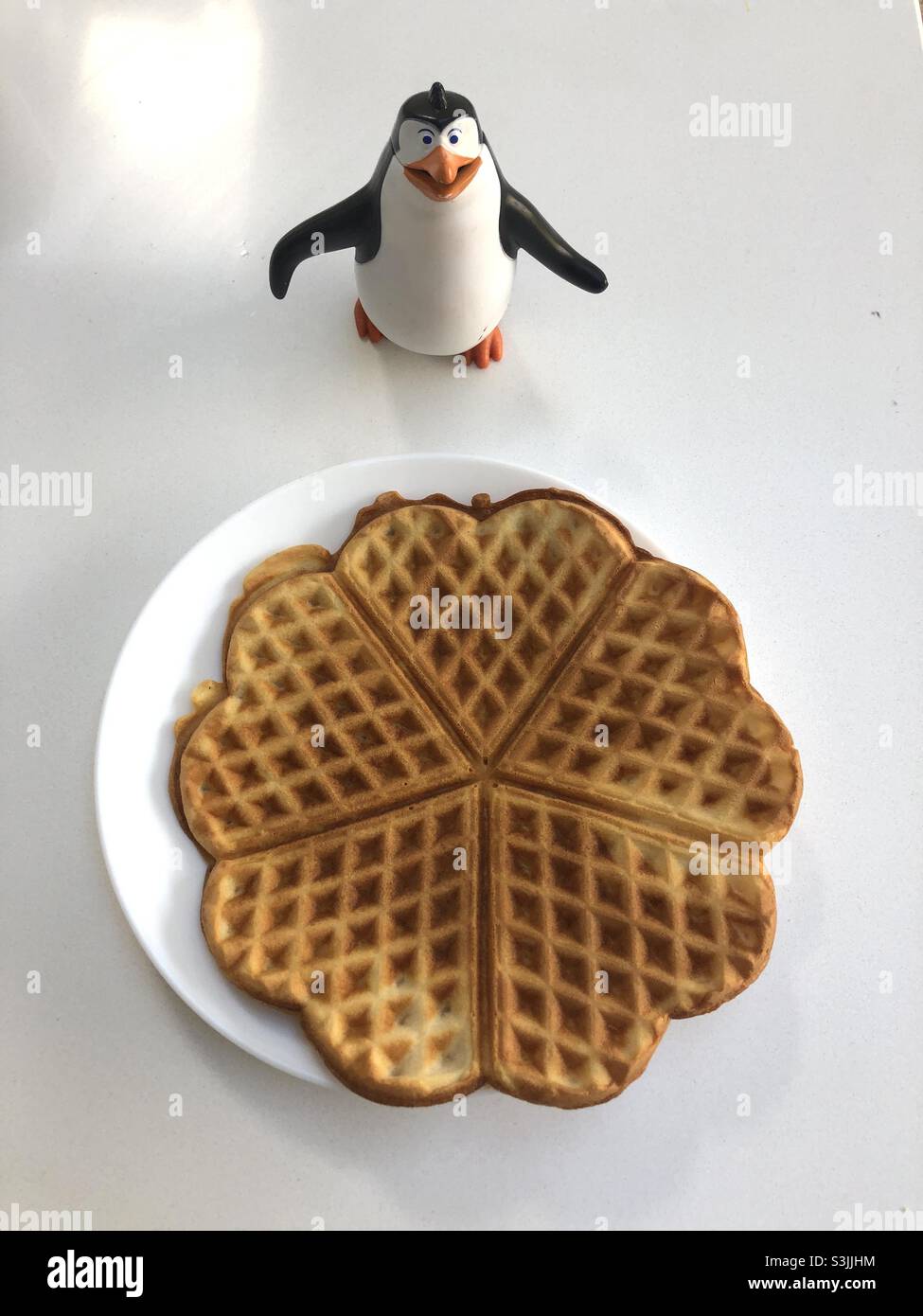 Waffle fatti in casa a forma di cuore e un pinguino figurine accanto ad esso - Immagine stock catturata con smartphone