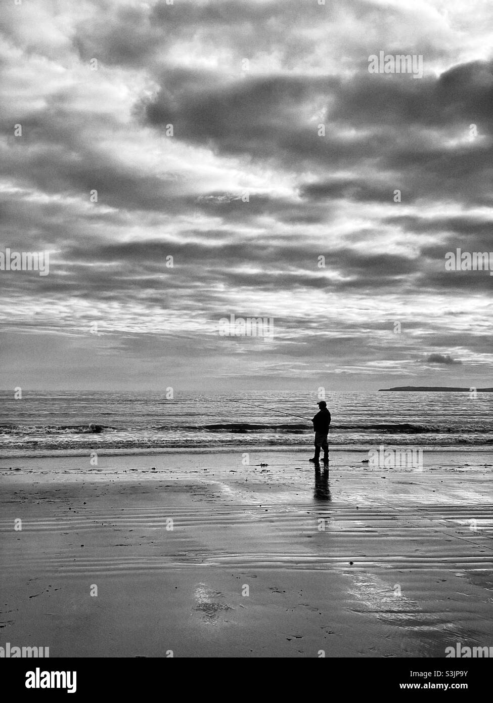 Lone pesca pescatore su una spiaggia gallese, ottobre. Foto Stock