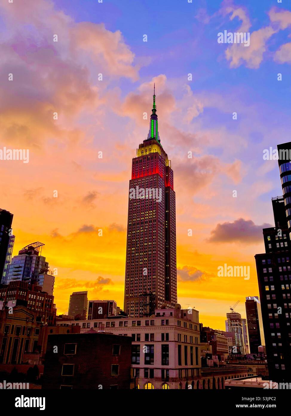 Un tramonto luminoso e colorato sulla città di New York con una silhouette dell'Empire state Building e di altri grattacieli Foto Stock