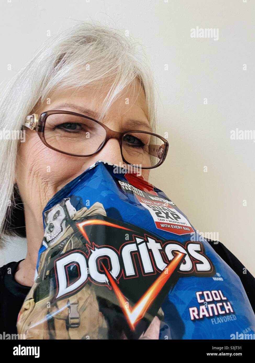 Donna con il naso e la bocca in un Doritos Cool Ranch chips - Immagine stock catturata con smartphone