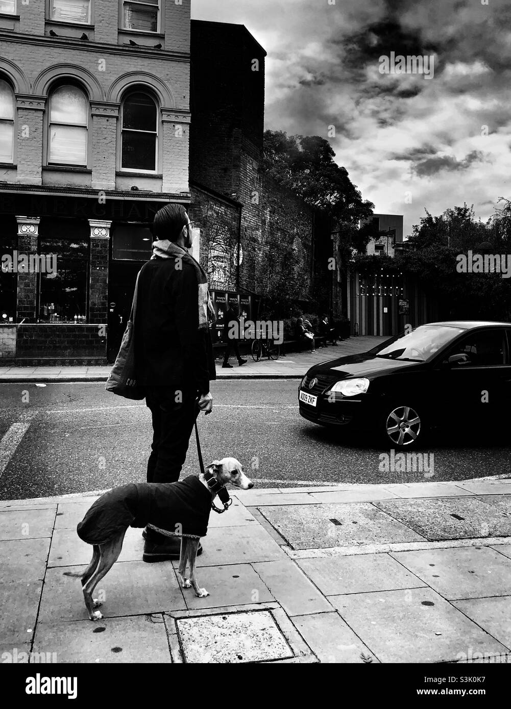 Uomo in piedi con il suo cane da levriero italiano sul marciapiede - Immagine stock catturata con smartphone