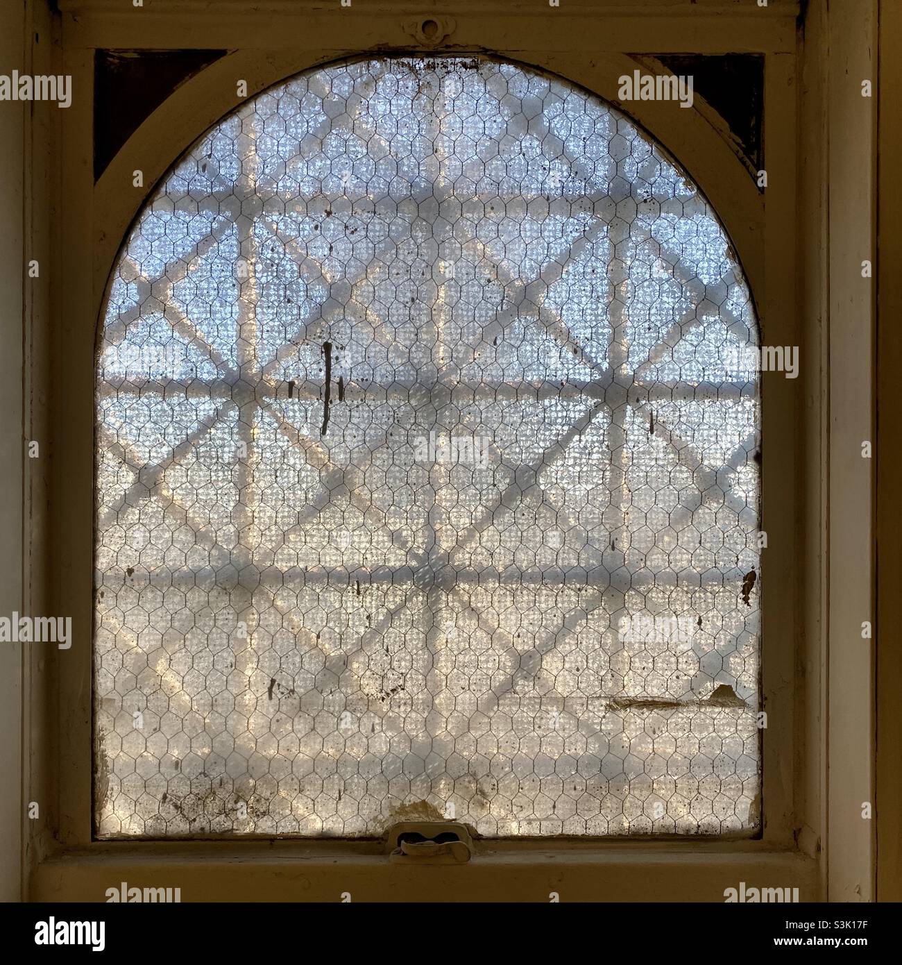 Finestra dell'edificio vintage con vetro di sicurezza smerigliato e motivo in ferro battuto all'esterno, che crea un astratto motivo grunge Foto Stock