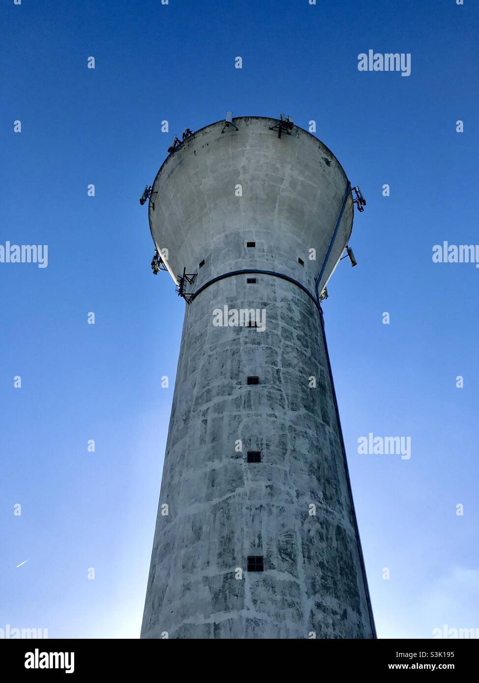 Vecchia torre d'acqua con radio e telefoni cellulari masts, contro il cielo blu chiaro. Les Yvelines, Francia. - Immagine stock catturata con smartphone