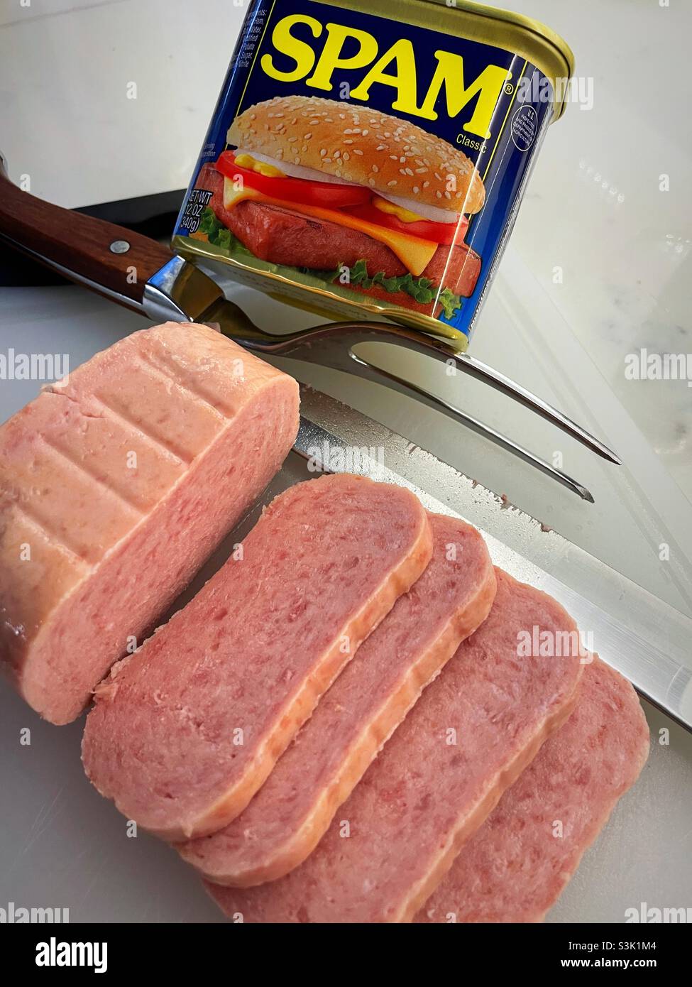 Fette di carne di maiale cotto spam su un tagliere con un coltello e forchetta, USA - Immagine stock catturata con smartphone