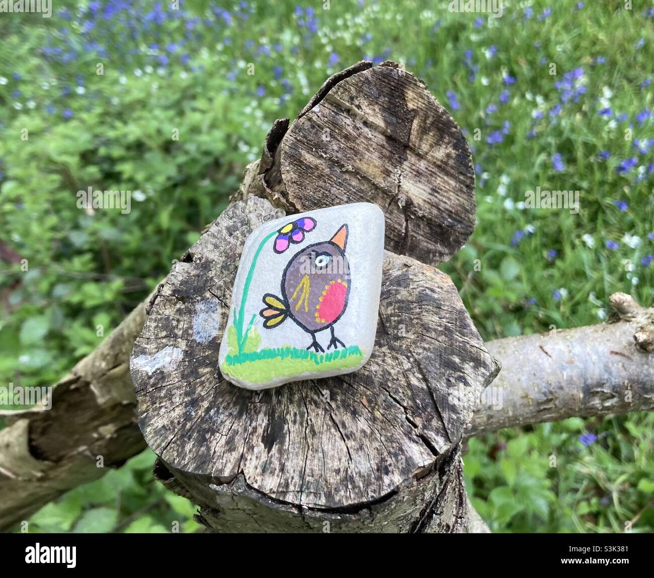 Una roccia di gentilezza raffigurante un uccello e un fiore Robin dipinto a mano, trovato in un ceppo di albero in Foxley Woods, Norfolk maggio 2021. Foto Stock