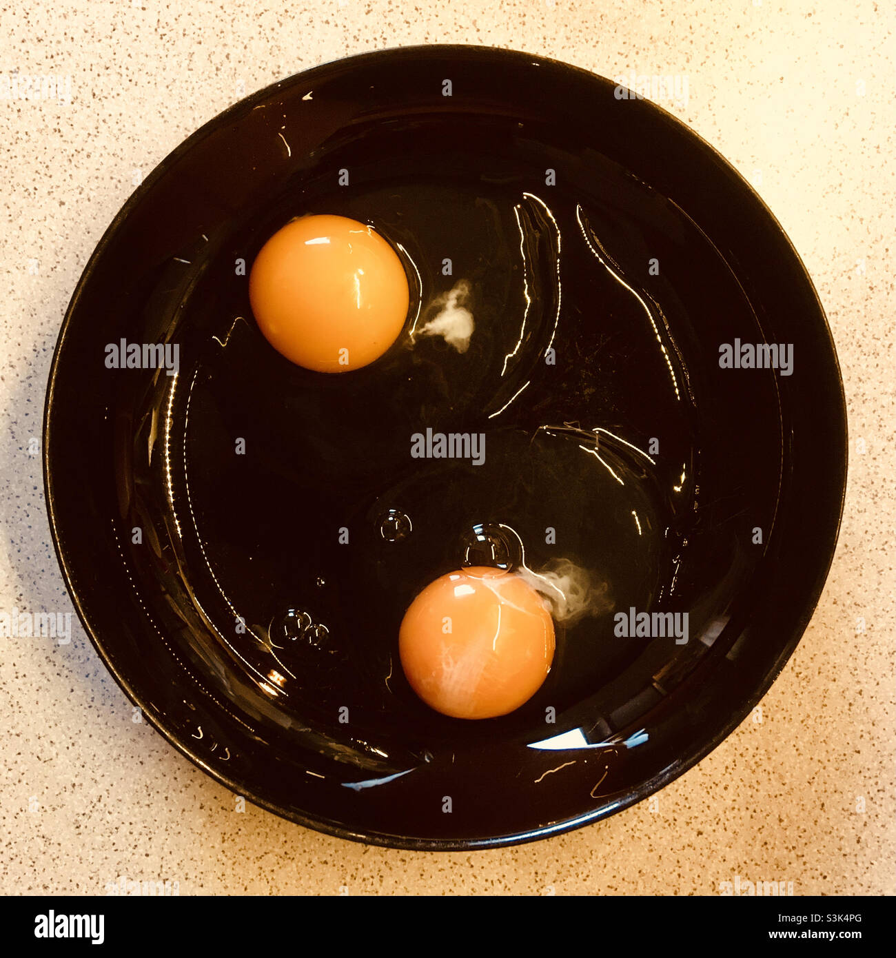 Due uova rotte su piatto nero con tuorlo - Immagine stock catturata con smartphone