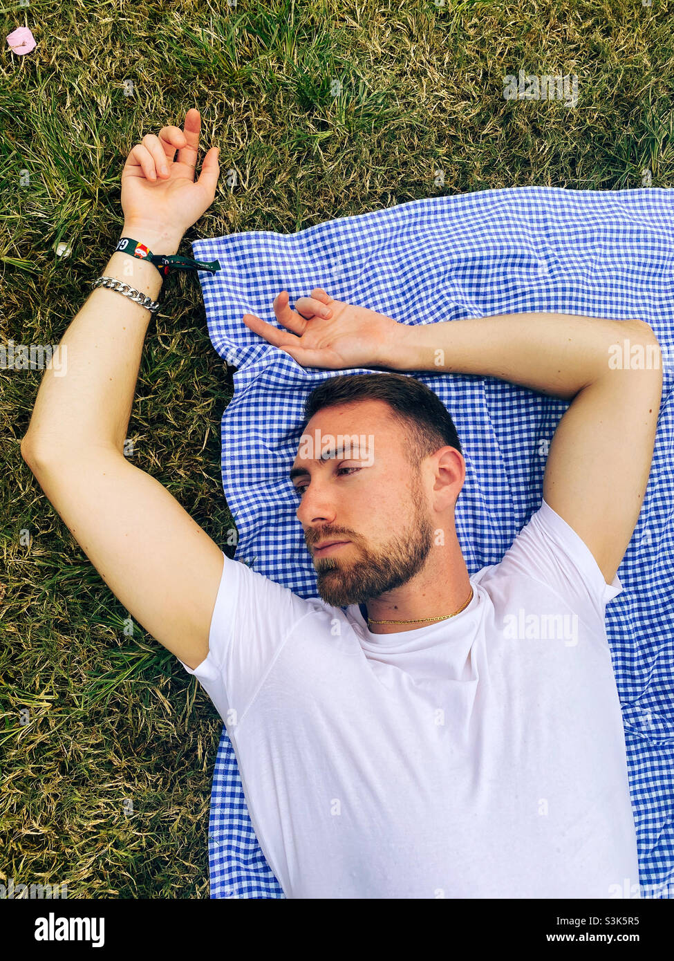 Uomo che posa su una coperta picnic giorno sognando Foto Stock