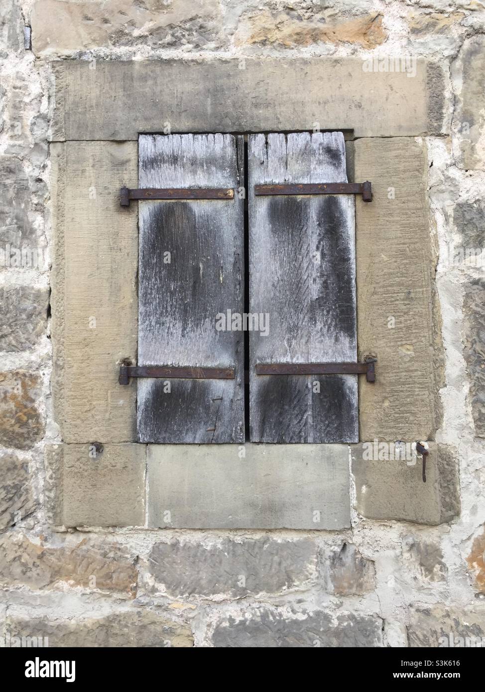 Serramento chiuso in legno intemperie in un antico edificio medievale Foto Stock