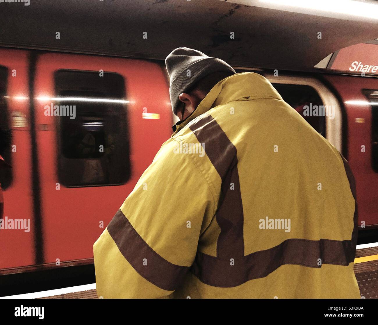 Uomo in gilet ad alta visibilità su una stazione di londra sotto terra Foto Stock
