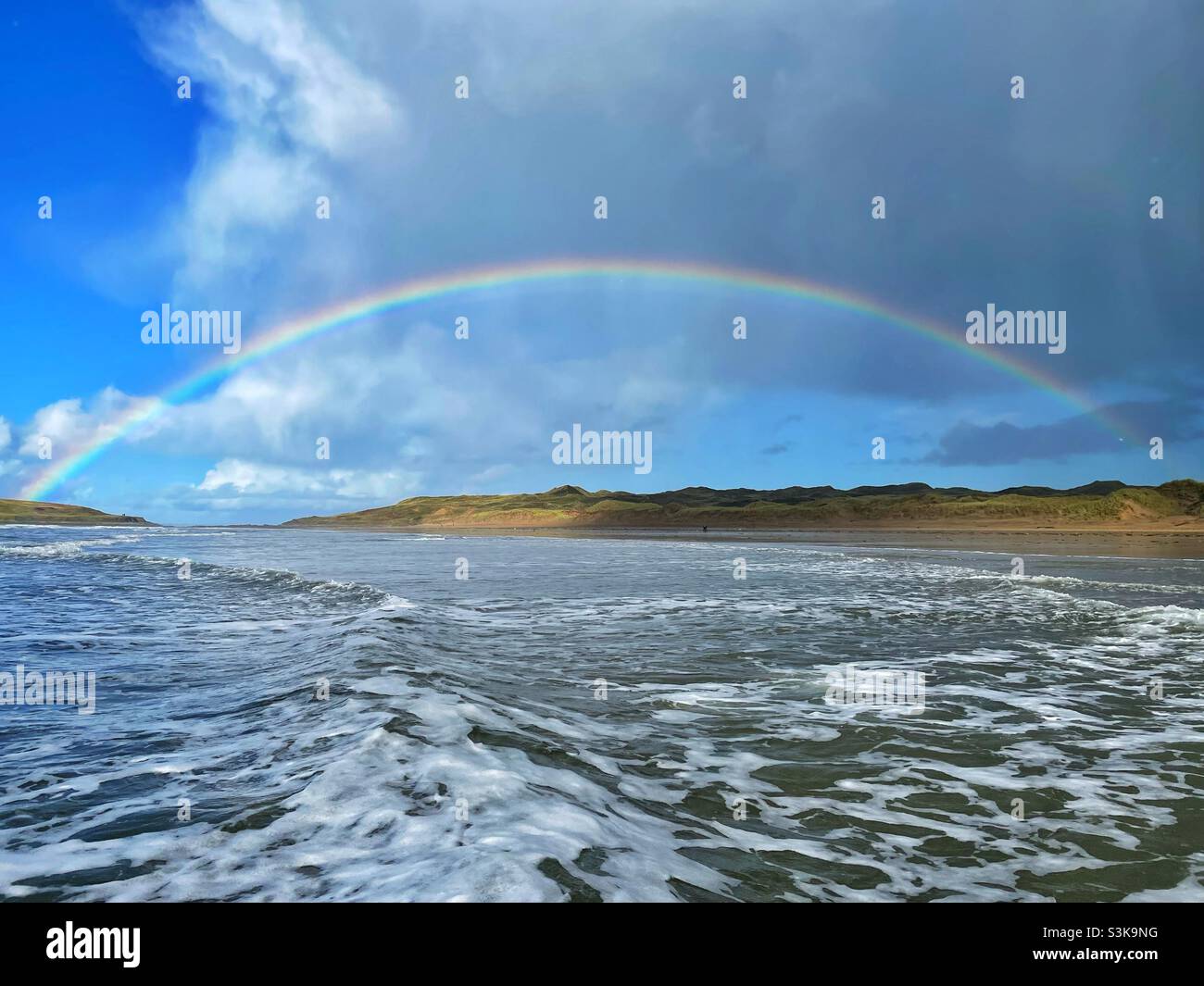 Arcobaleno sulla spiaggia di Llangennith e Burry Holms, Gower, Swansea, Galles sud-occidentale, ottobre. Foto Stock