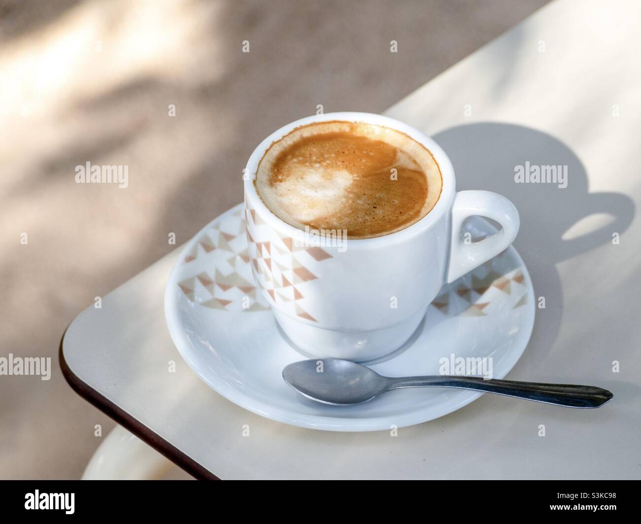 Una tazza di caffè perfetta su un piatto con un cucchiaio. Caffè all'aperto drink. Caffè sul tavolo - Immagine stock catturata con smartphone