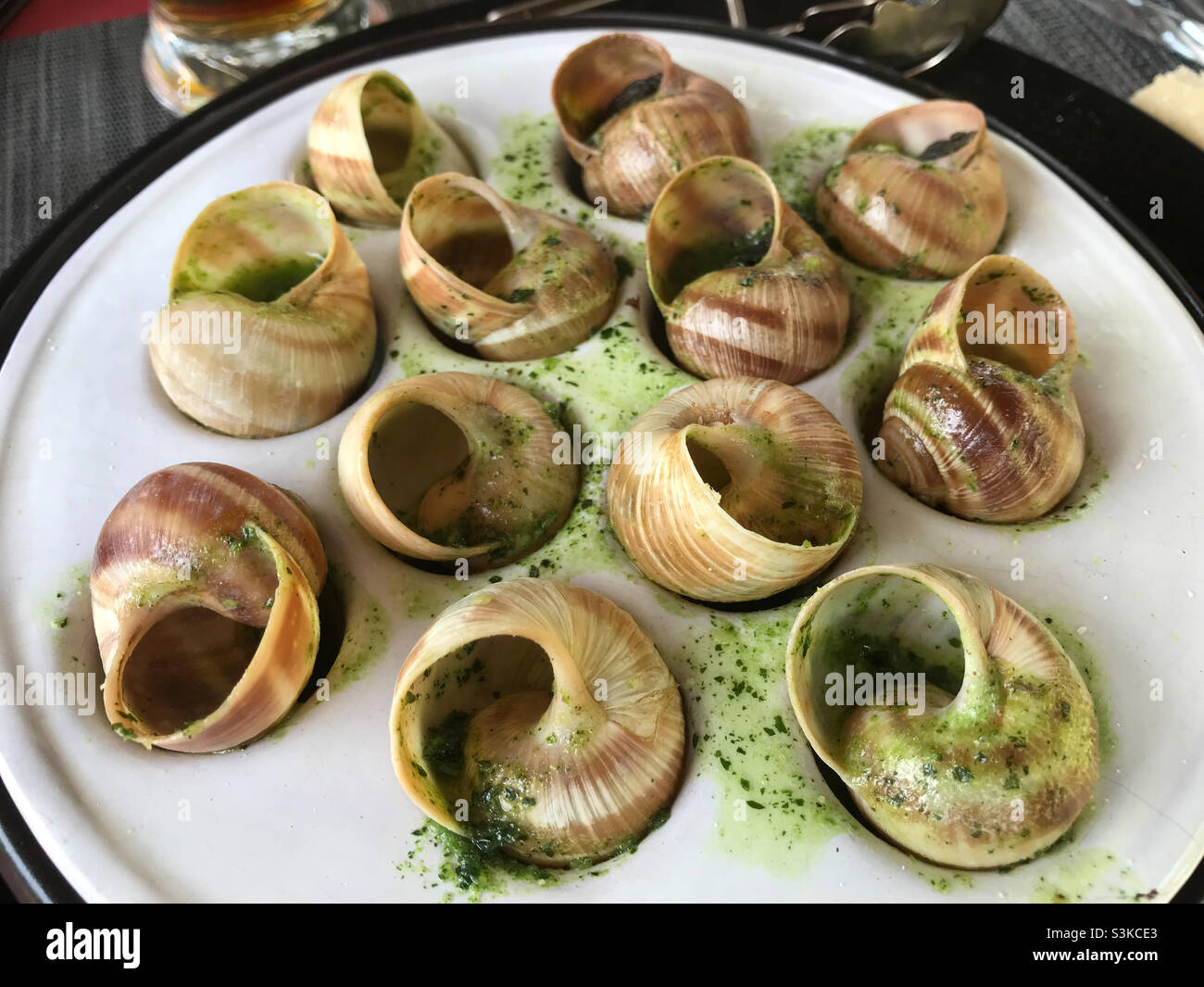 Lumache in prezzemolo al burro e salsa all'aglio su piatto in un ristorante - Immagine stock catturata con smartphone