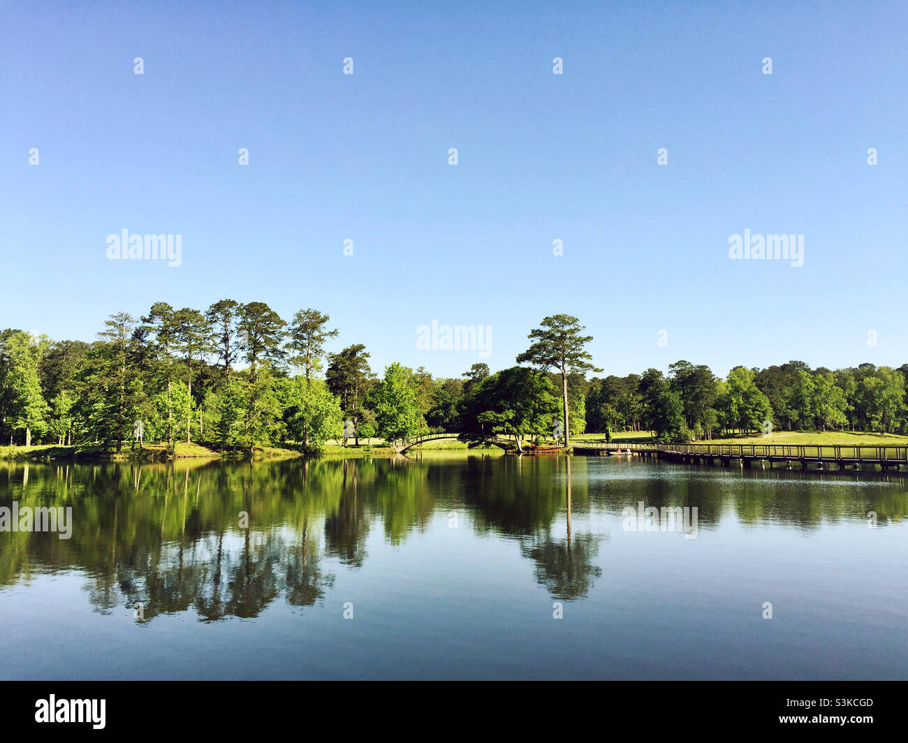 Splendida vista panoramica di un lago con riflessi. La gente pesca in una piccola barca. Foto Stock