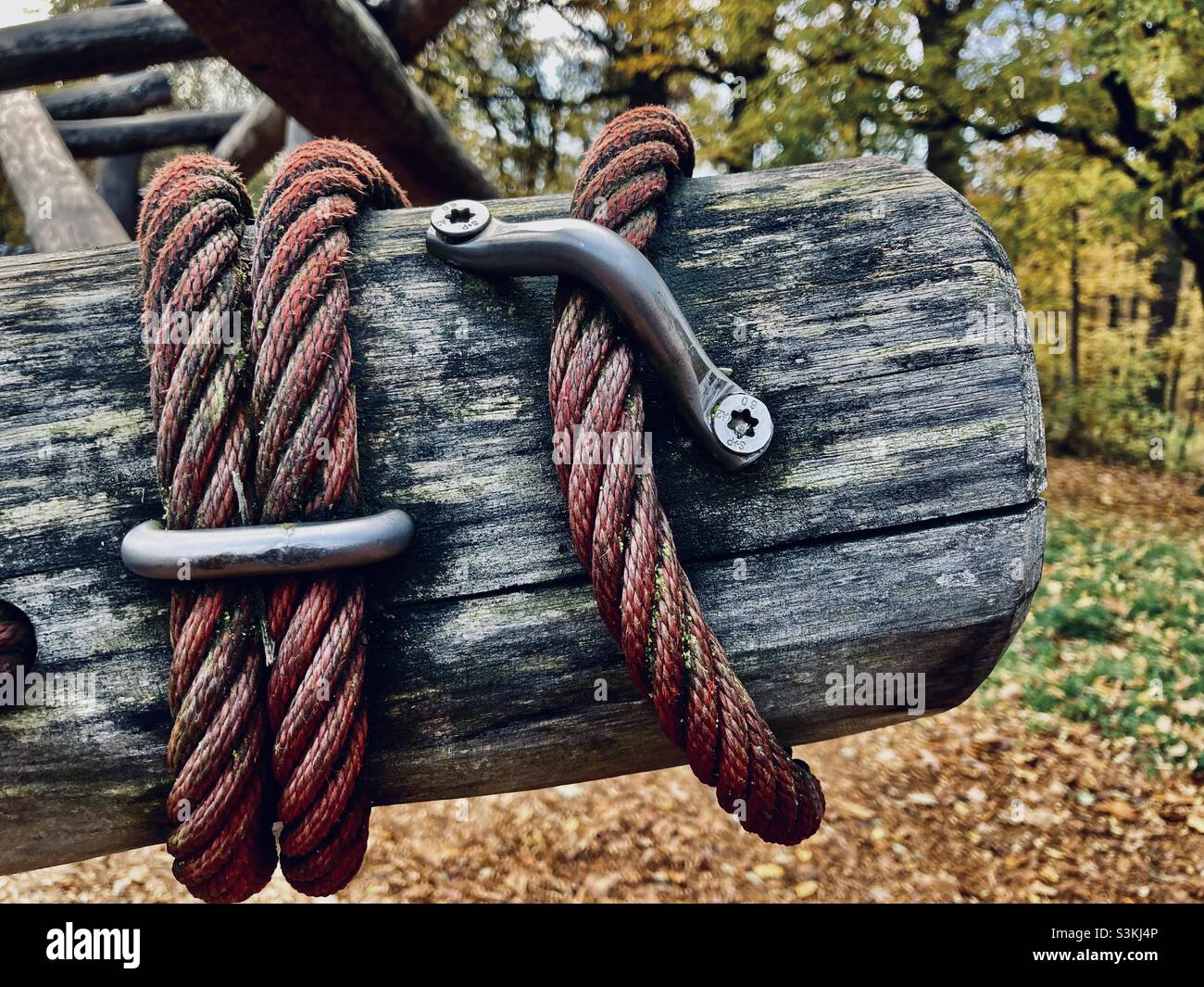 Una corda rossa è avvolta intorno ad una trave grigia di legno - Immagine stock catturata con smartphone