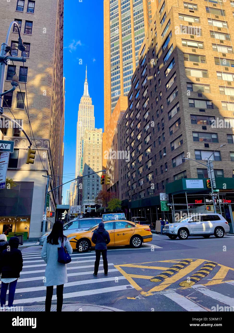 Persone e automobili a un incrocio con una vista dell'Empire state Building, NewYork City Foto Stock