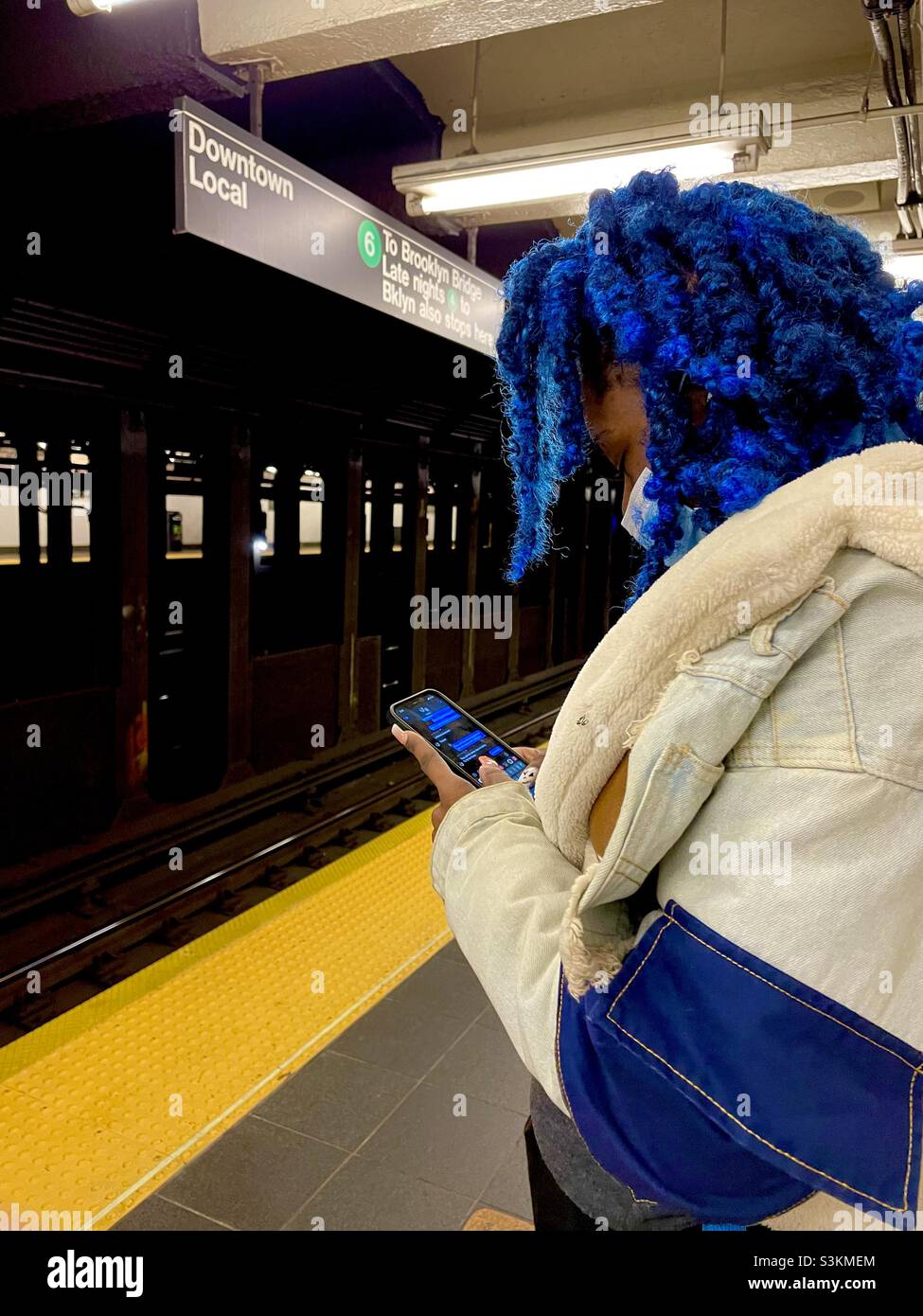 Una donna dai capelli blu aspetta la metropolitana a New York City Foto Stock