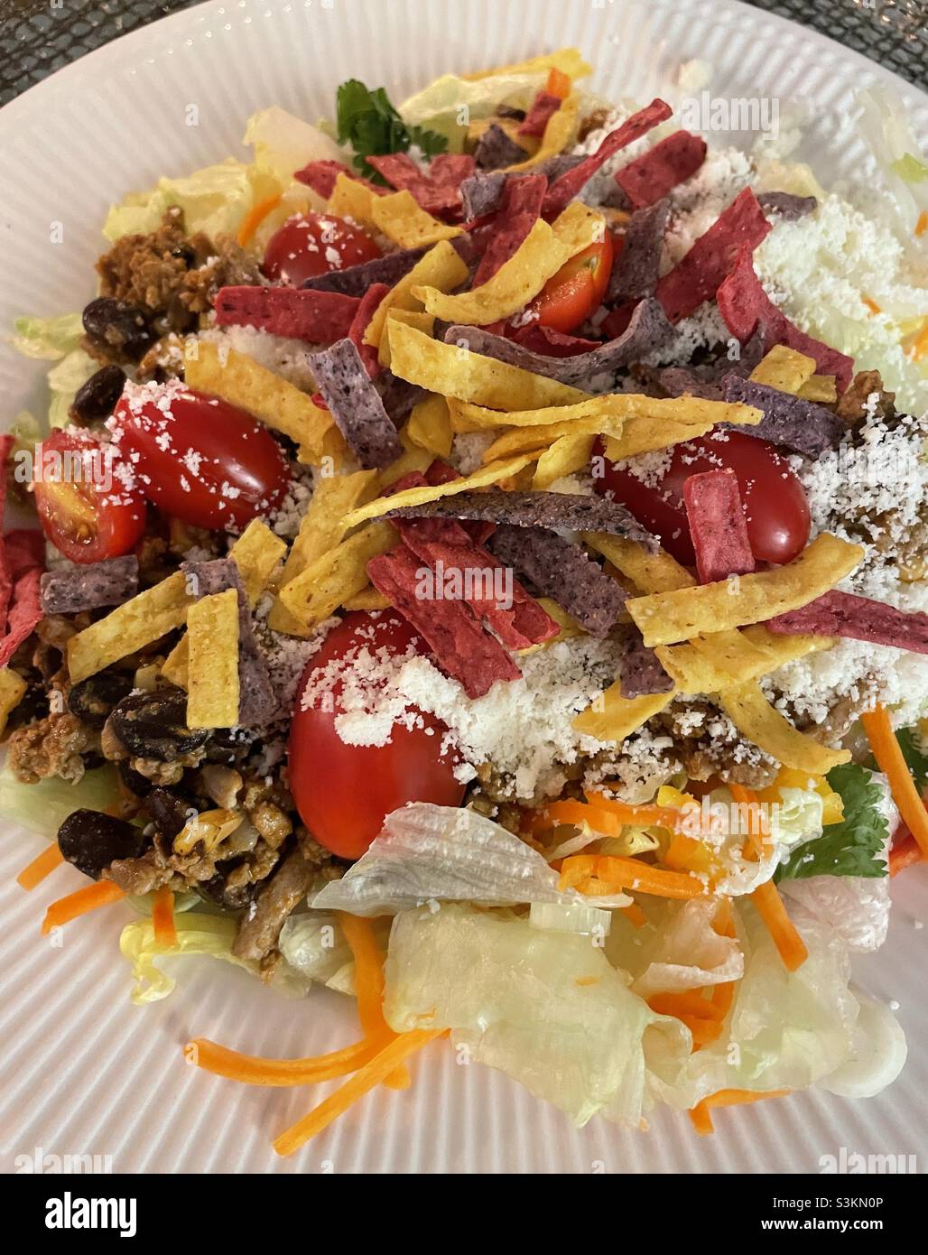 Primo piano di una gustosa insalata taco guarnita con tortilla e formaggio grattugiato Foto Stock