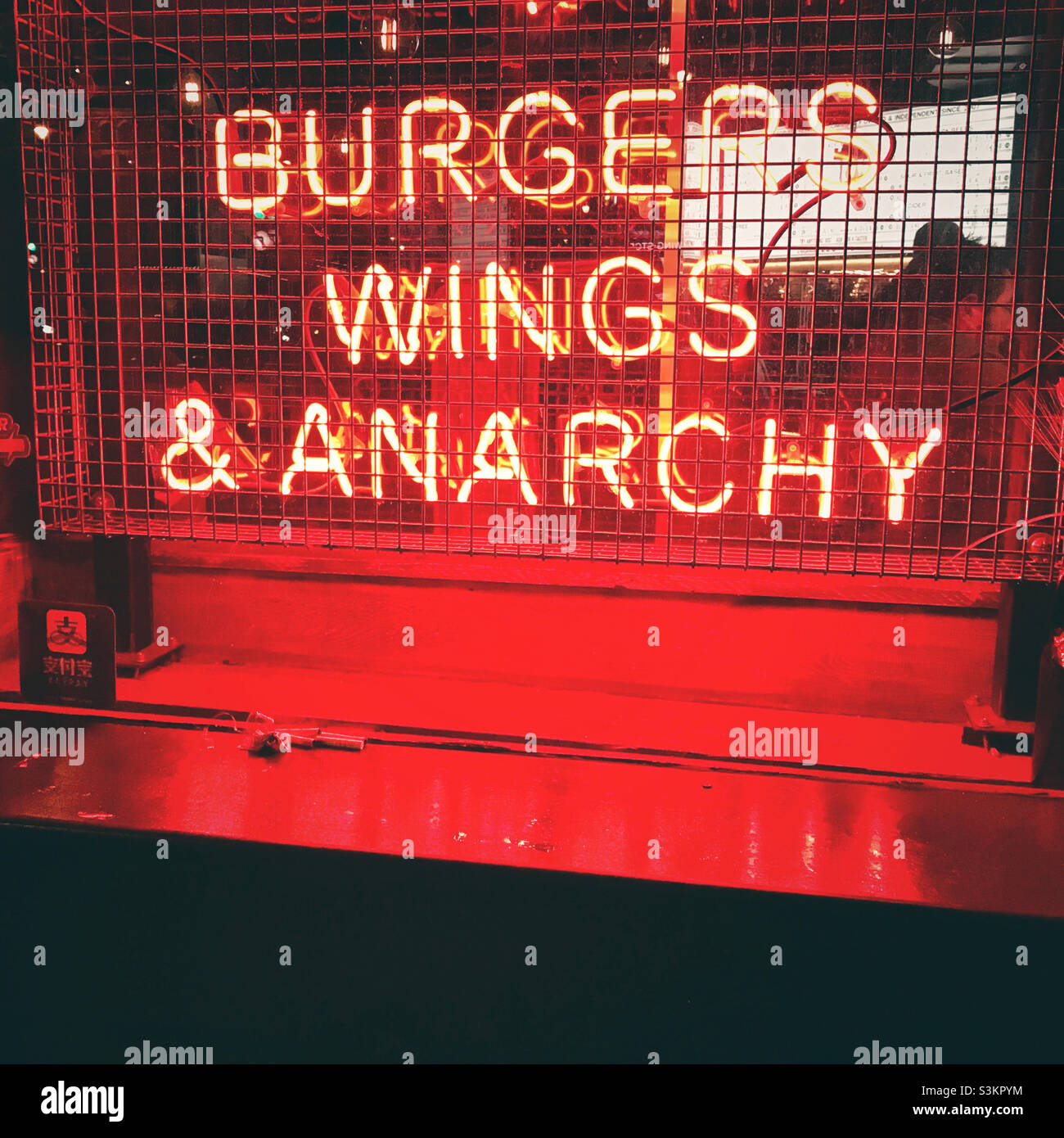 Un cartello al neon con la scritta "Burgers, Wings and Anarchy" in un ristorante londinese Foto Stock