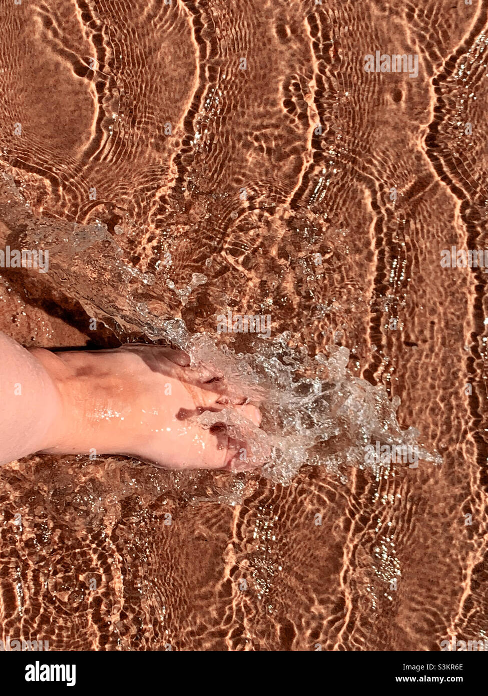 Facendo un tuffo, le punte che tuffano nell'acqua. Un piede che si tuffa nell'acqua di mare sulla spiaggia. Bagnando i piedi Foto Stock