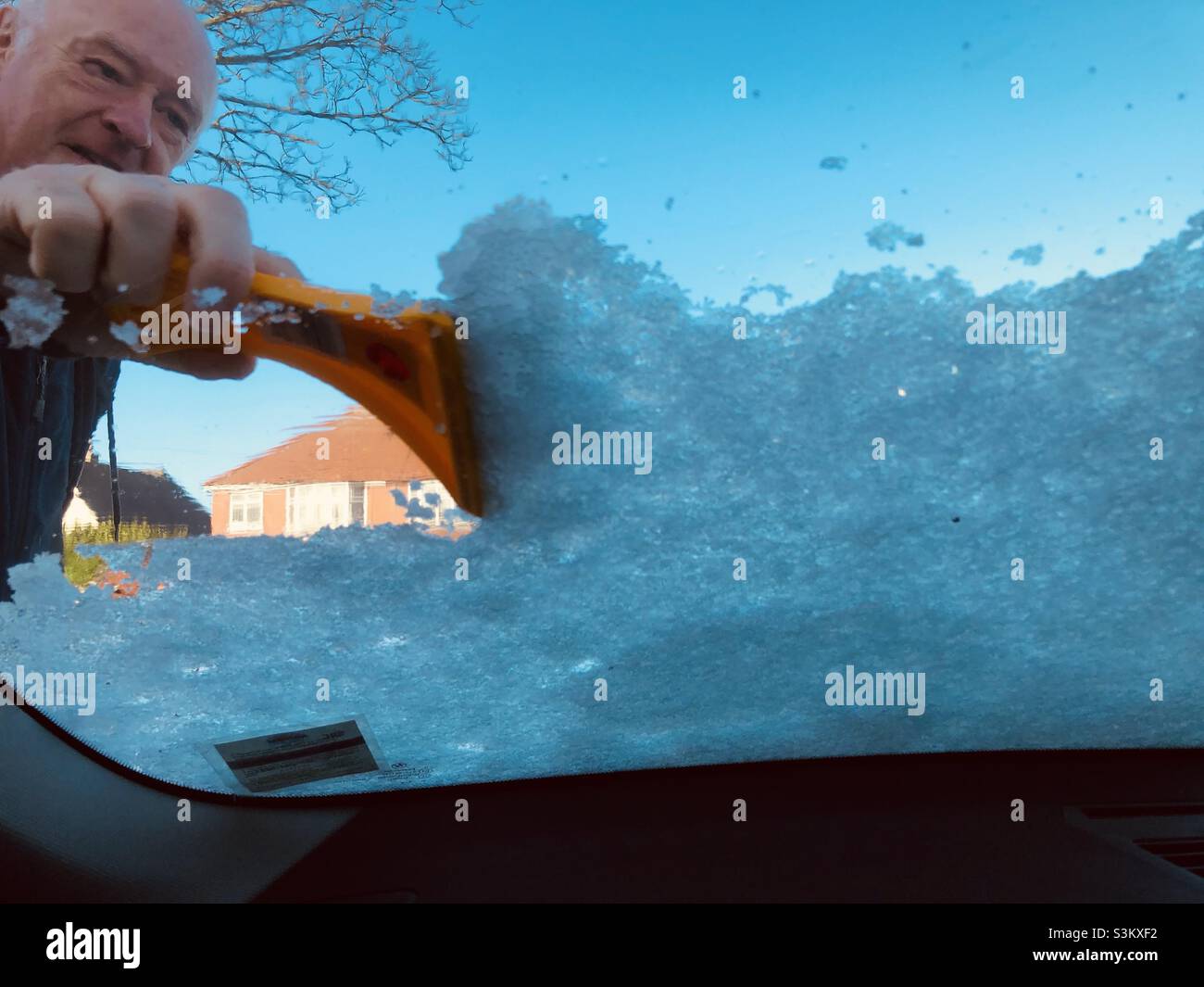 Uomo che sgombrano la neve dal parabrezza di un'auto - Immagine stock catturata con smartphone