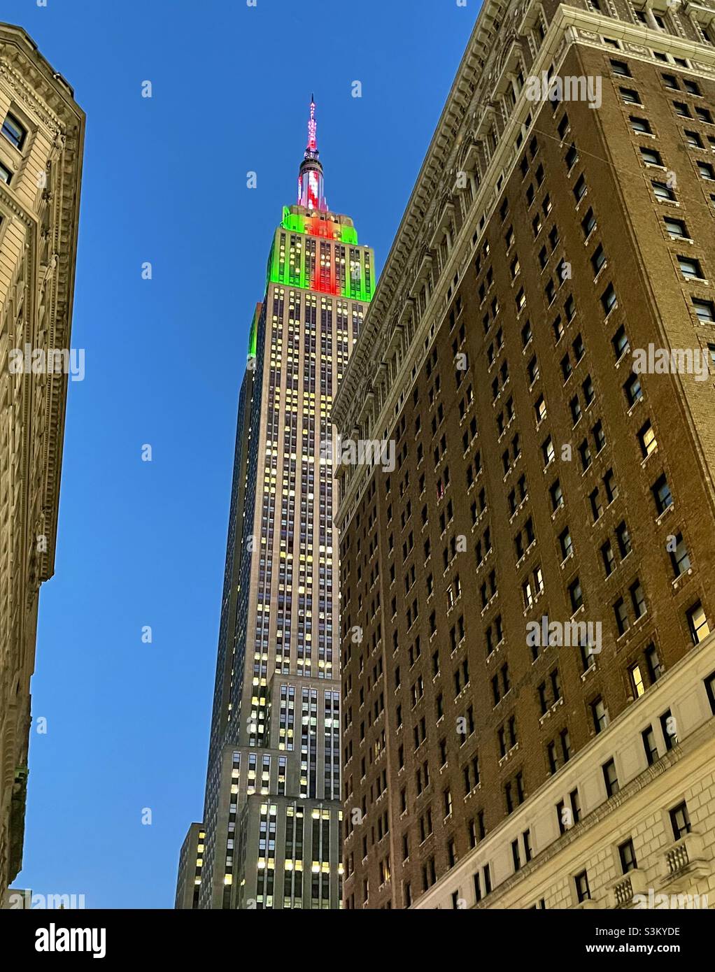 I colori di Natale sulle luci della torre dell'Empire state Building come visto da Herald Square a New York City - Immagine stock catturata con smartphone