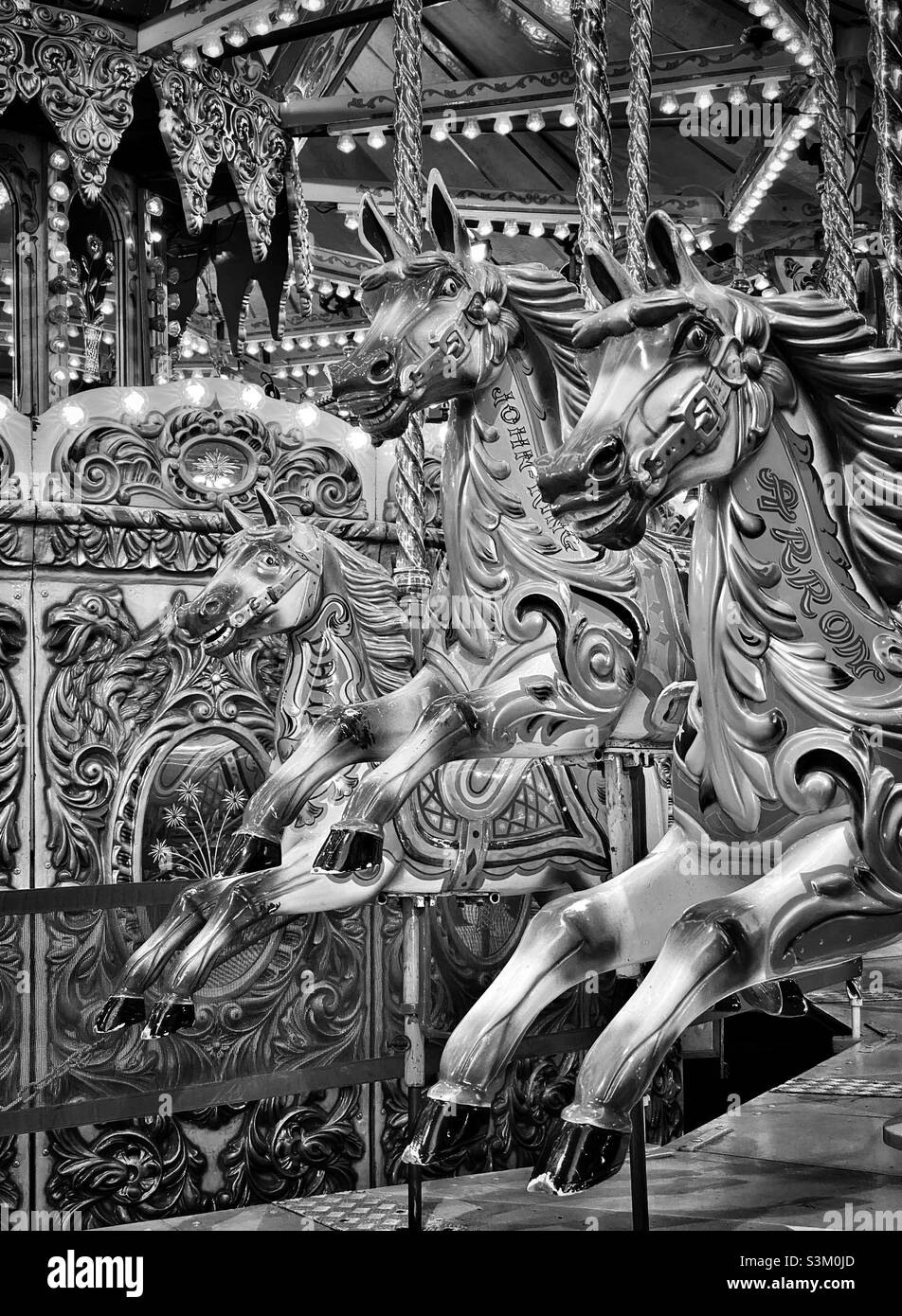 Tre cavalli attendono i cavalieri durante un giro in giostra Merry Go Round in una fiera divertente. Un'immagine monocromatica ad alto contrasto. Ricordi dell'infanzia. Foto ©️ COLIN HOSKINS. Foto Stock