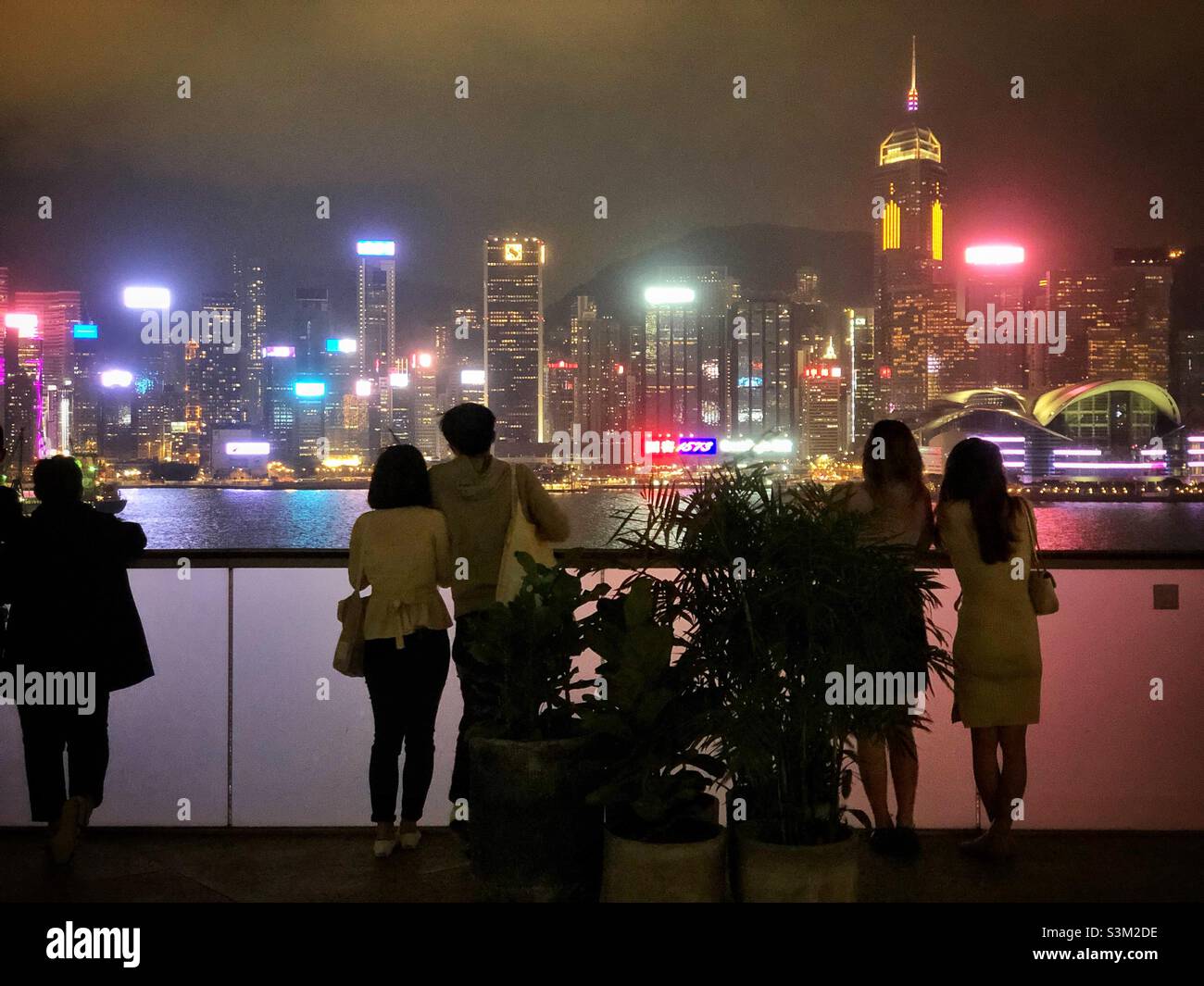 Gli amanti dello shopping e i turisti godono del panorama dello skyline dell'Isola di Hong Kong di notte da K11 ARTUS, un centro commerciale a Tsim Sha Tsui, Kowloon Foto Stock