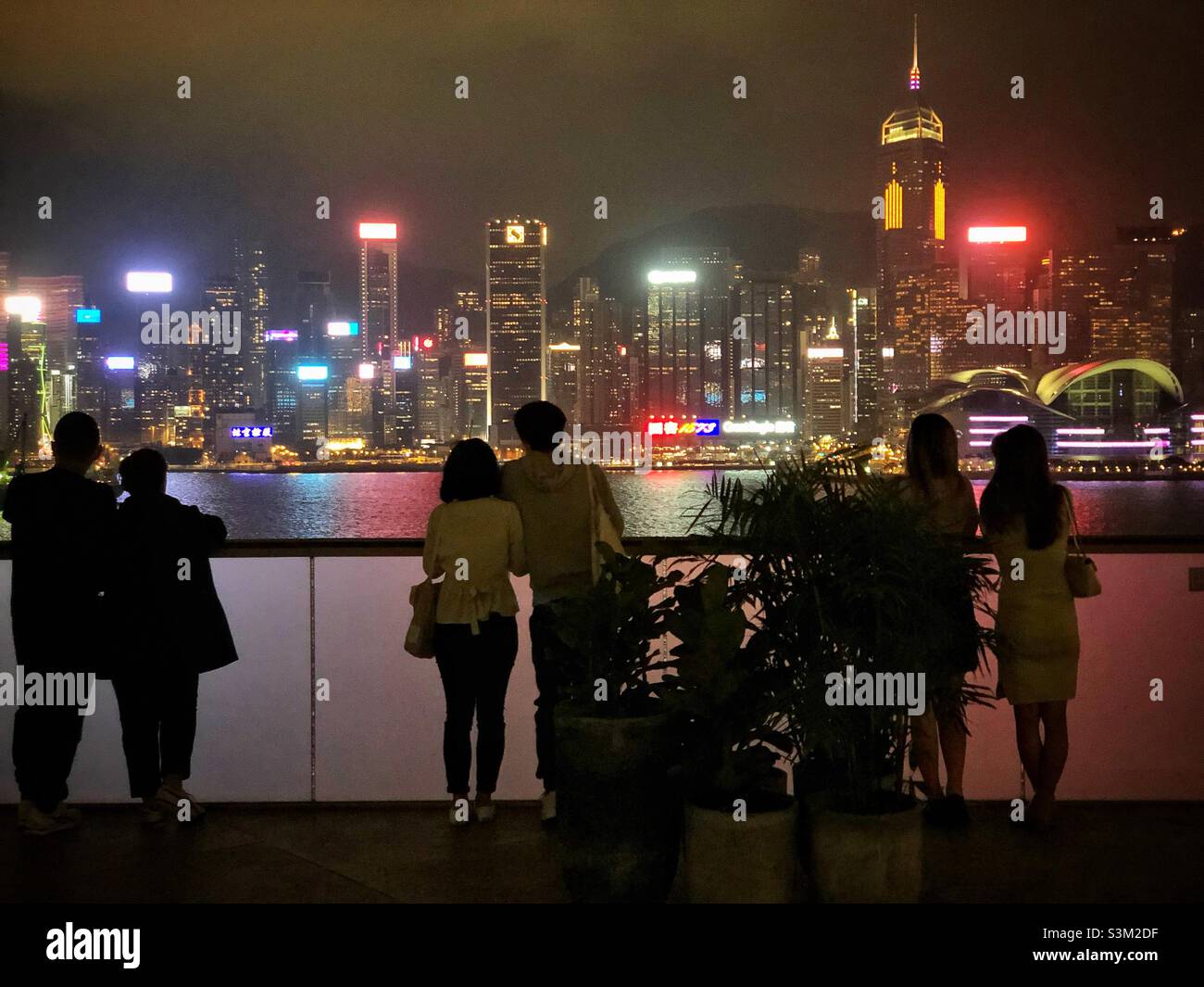 Gli amanti dello shopping e i turisti godono del panorama dello skyline dell'Isola di Hong Kong di notte da K11 ARTUS, un centro commerciale a Tsim Sha Tsui, Kowloon Foto Stock