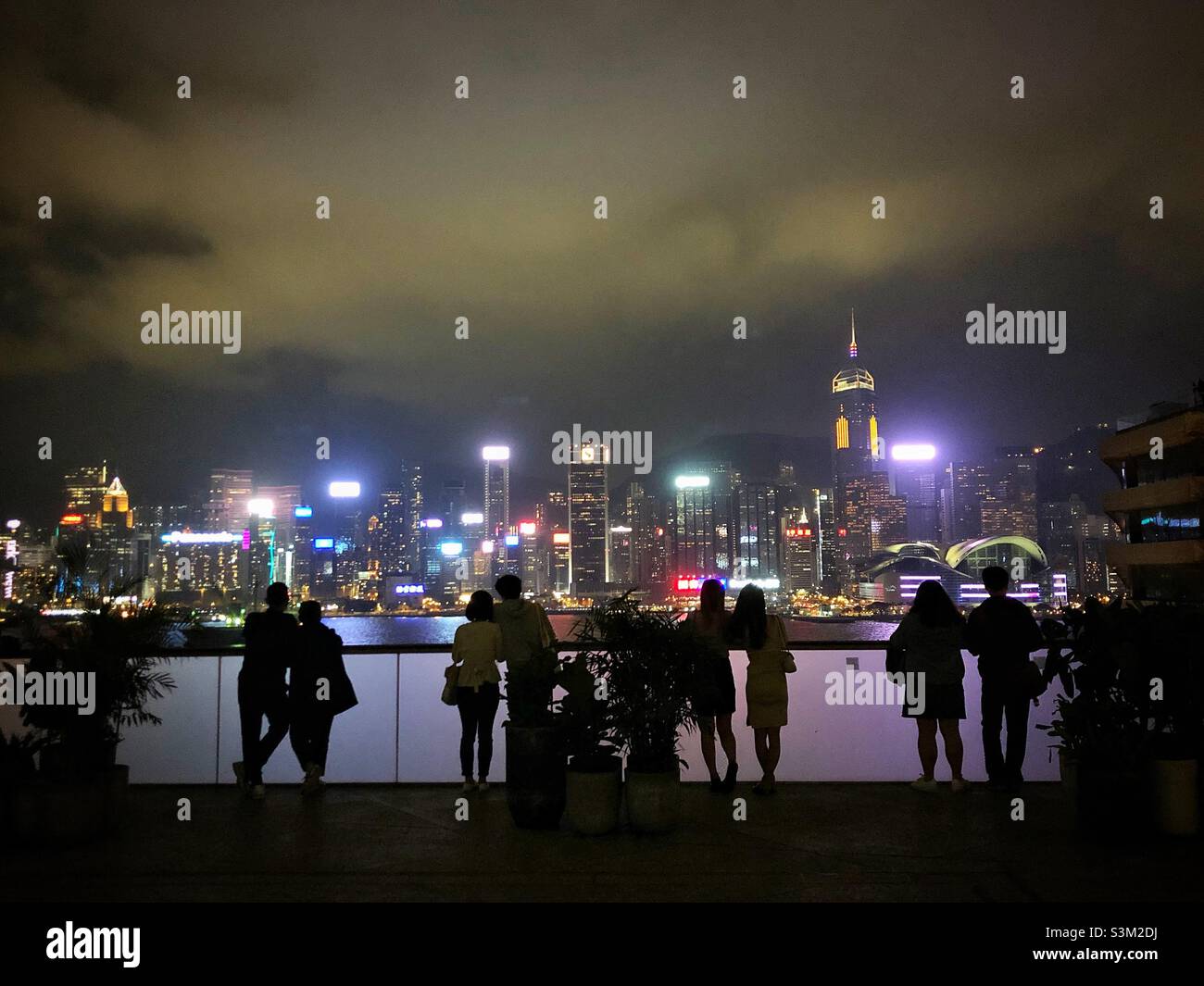 Gli amanti dello shopping e i turisti godono del panorama dello skyline dell'Isola di Hong Kong di notte da K11 ARTUS, un centro commerciale a Tsim Sha Tsui, Kowloon Foto Stock