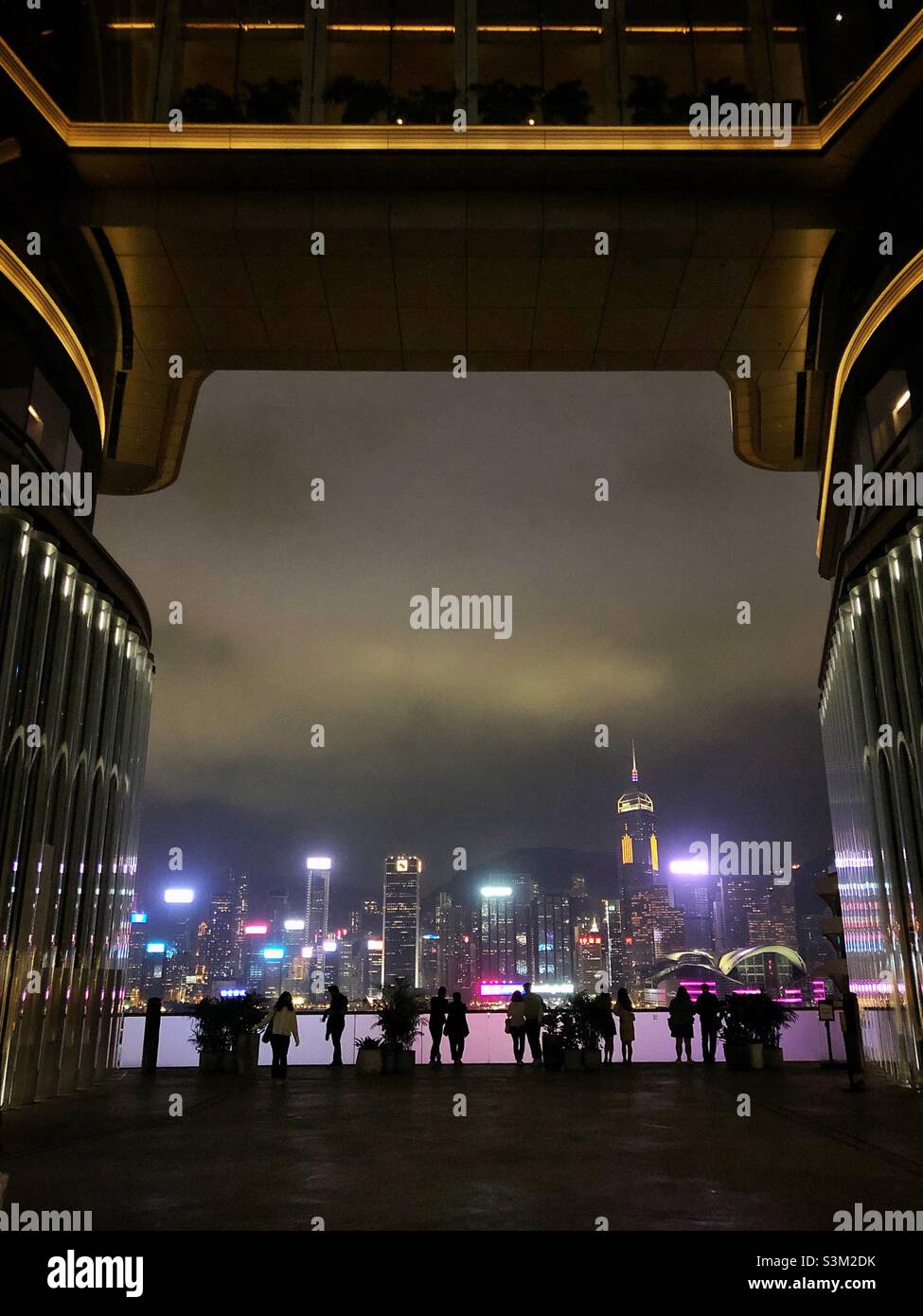 Gli amanti dello shopping e i turisti godono del panorama dello skyline dell'Isola di Hong Kong di notte da K11 ARTUS, un centro commerciale a Tsim Sha Tsui, Kowloon Foto Stock