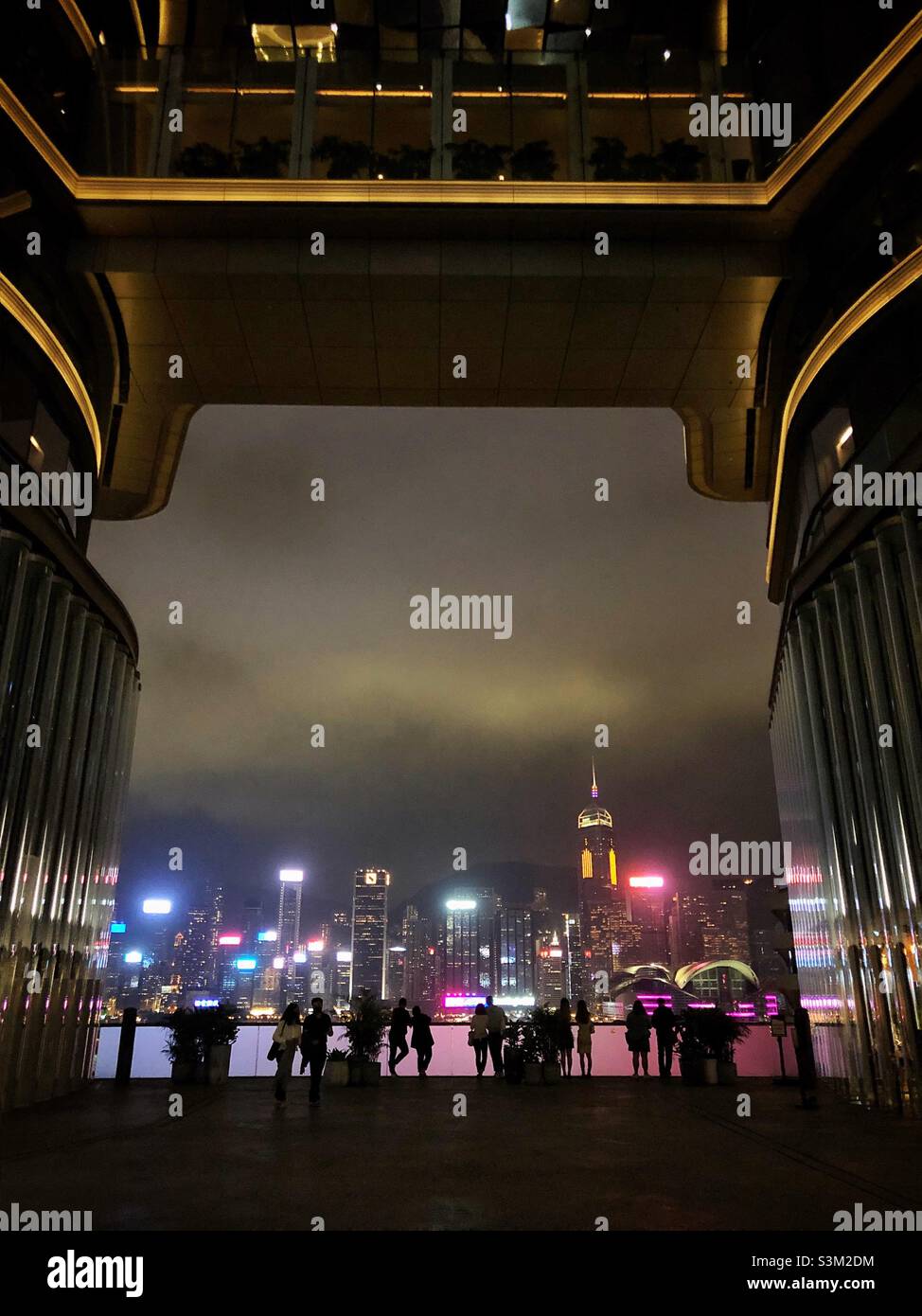 Gli amanti dello shopping e i turisti godono del panorama dello skyline dell'Isola di Hong Kong di notte da K11 ARTUS, un centro commerciale a Tsim Sha Tsui, Kowloon Foto Stock