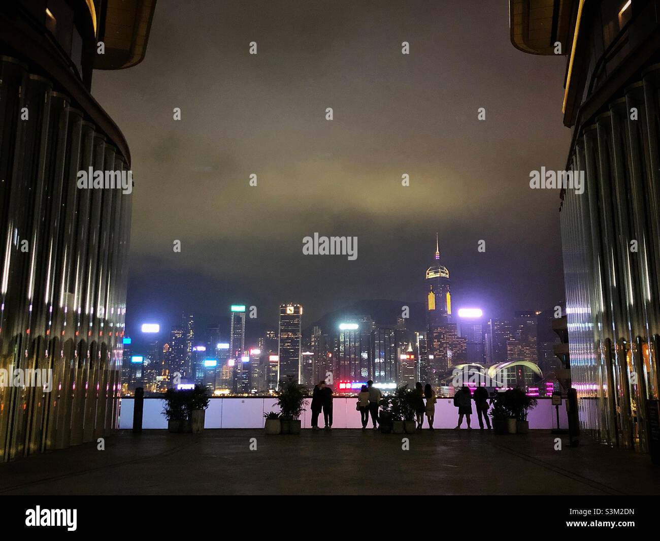 Gli amanti dello shopping e i turisti godono del panorama dello skyline dell'Isola di Hong Kong di notte da K11 ARTUS, un centro commerciale a Tsim Sha Tsui, Kowloon Foto Stock